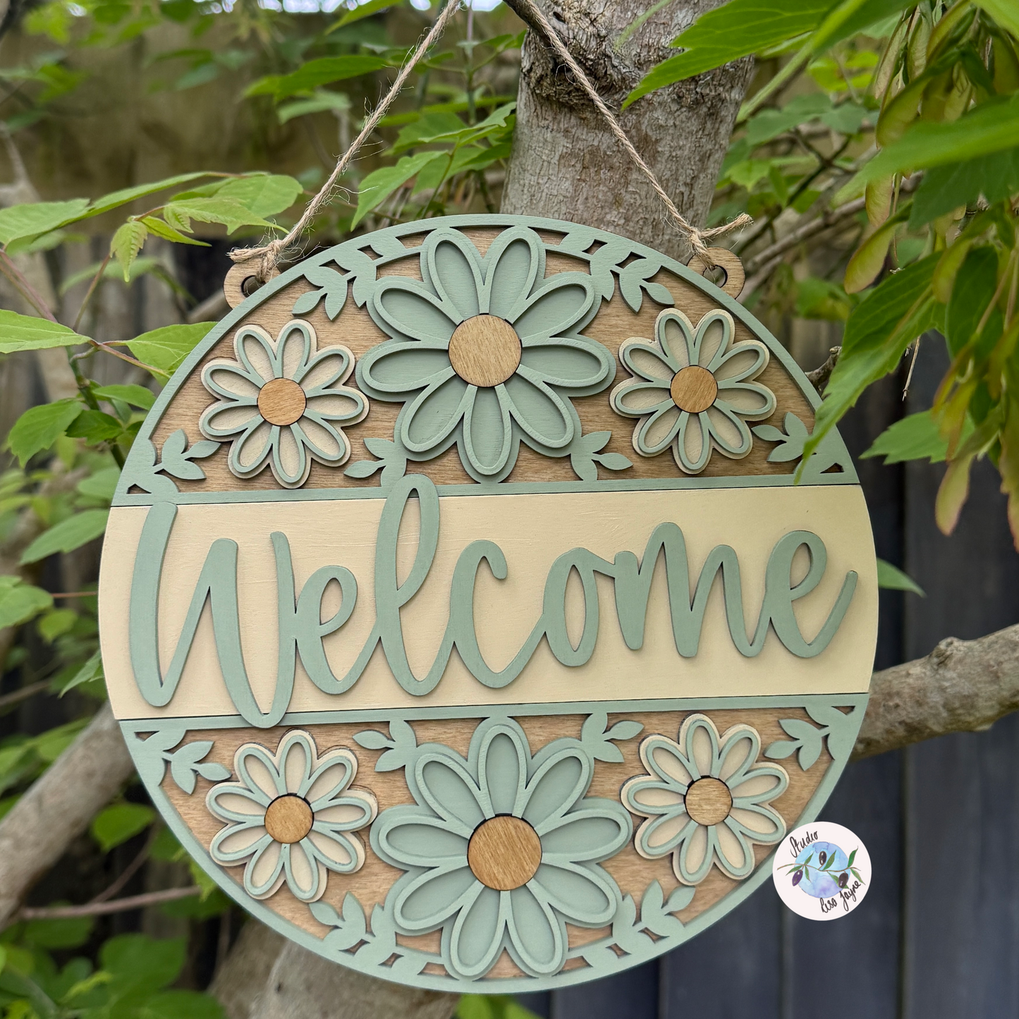 Welcome/Croeso Floral Handmade Hanging Wooden Sign - cream and green chalk paint flowers with wood stained accents. Hanging in nature