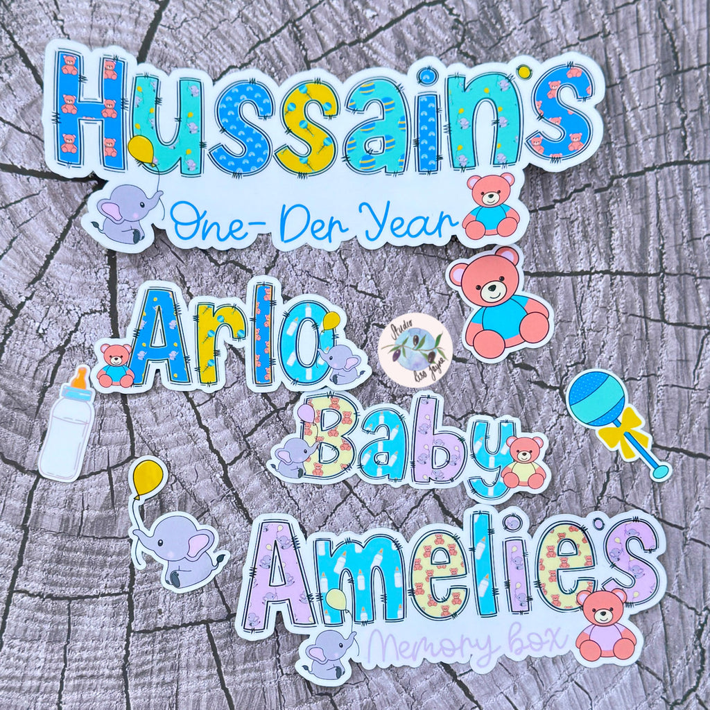 Colorful baby-themed stickers with text on a wooden background