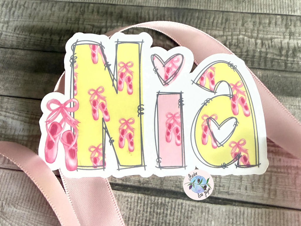 Sticker with 'Nia' design featuring ballet shoes and hearts on a wooden surface