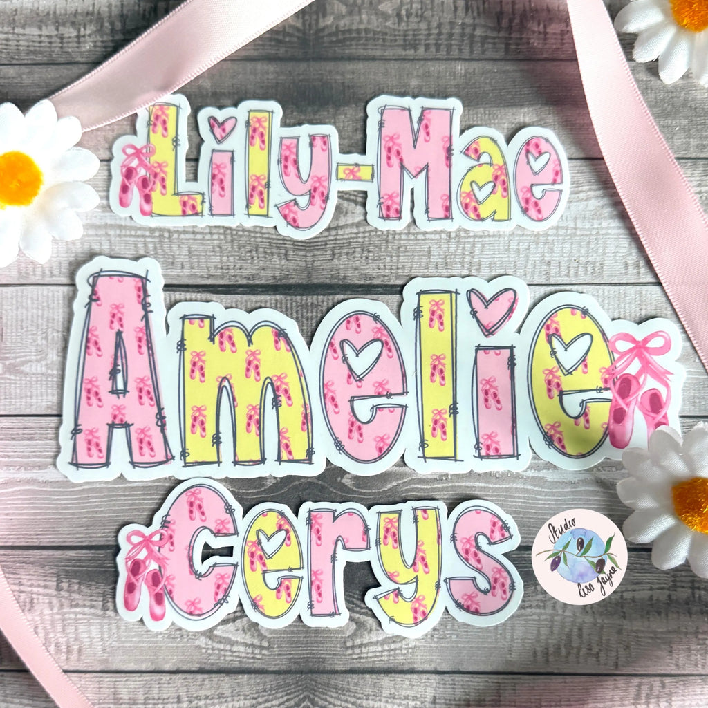 Colorful ballet name stickers on a wooden surface with flowers and ribbons.  Pink and yellow