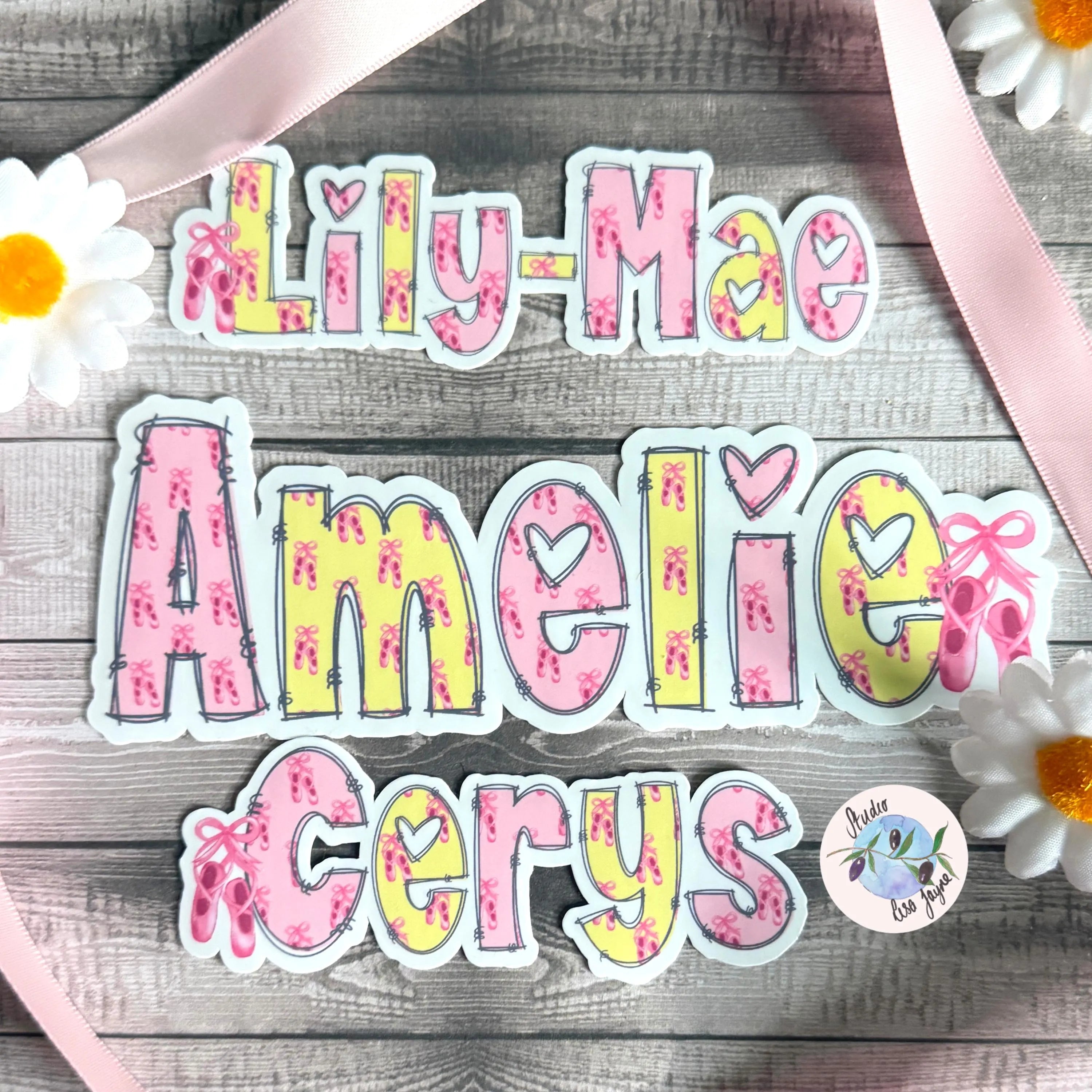 Colorful ballet name stickers on a wooden surface with flowers and ribbons.  Pink and yellow