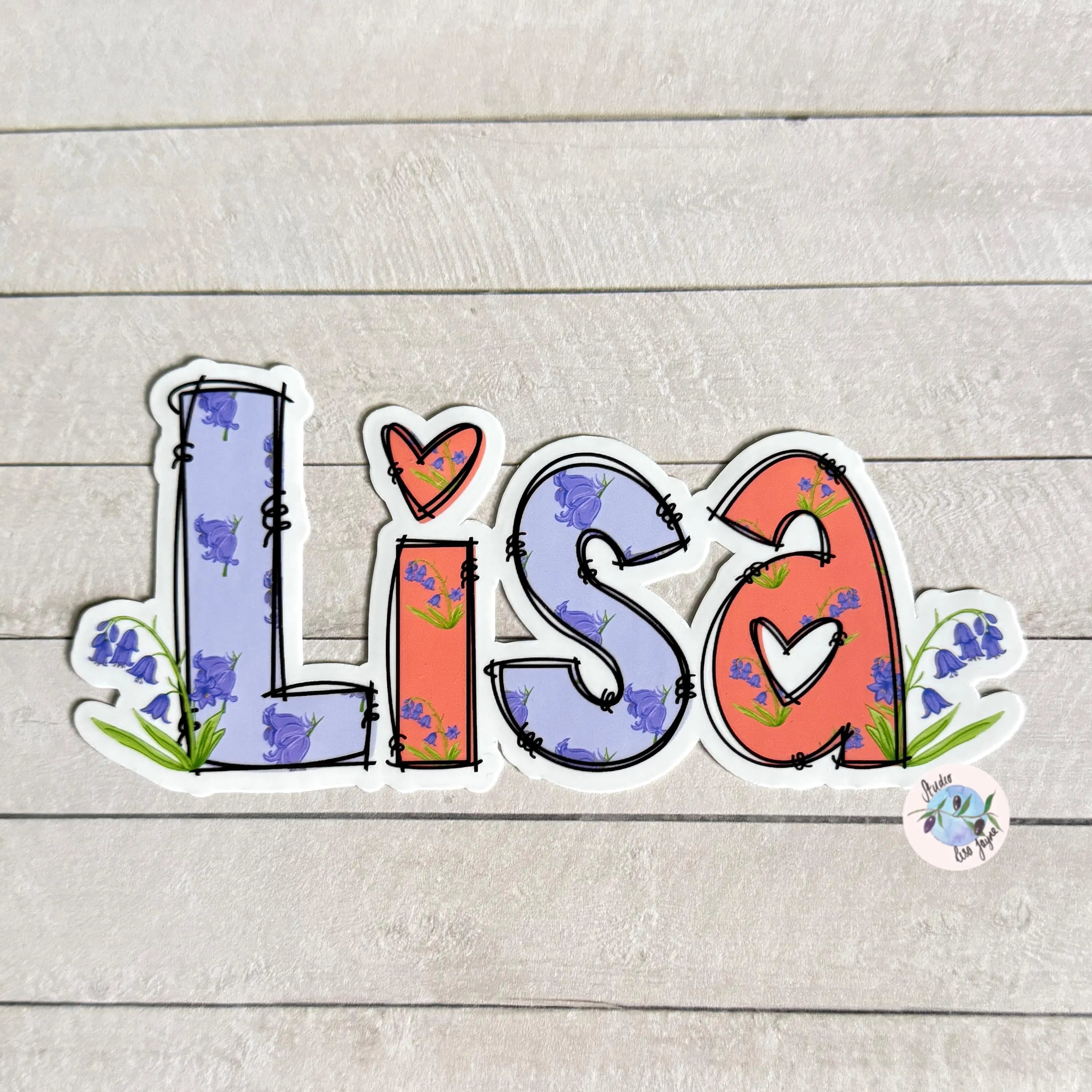 Colorful 'Lisa' name sticker with floral patterns on a wooden surface