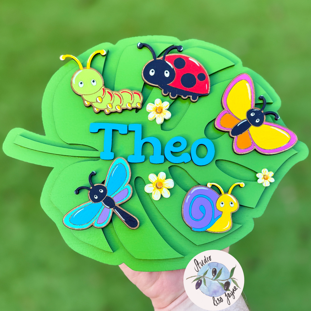 Personalised leaf-shaped bedroom nameplate with colourful hand painted insects and then name Theo in blue.  Ideal for boys