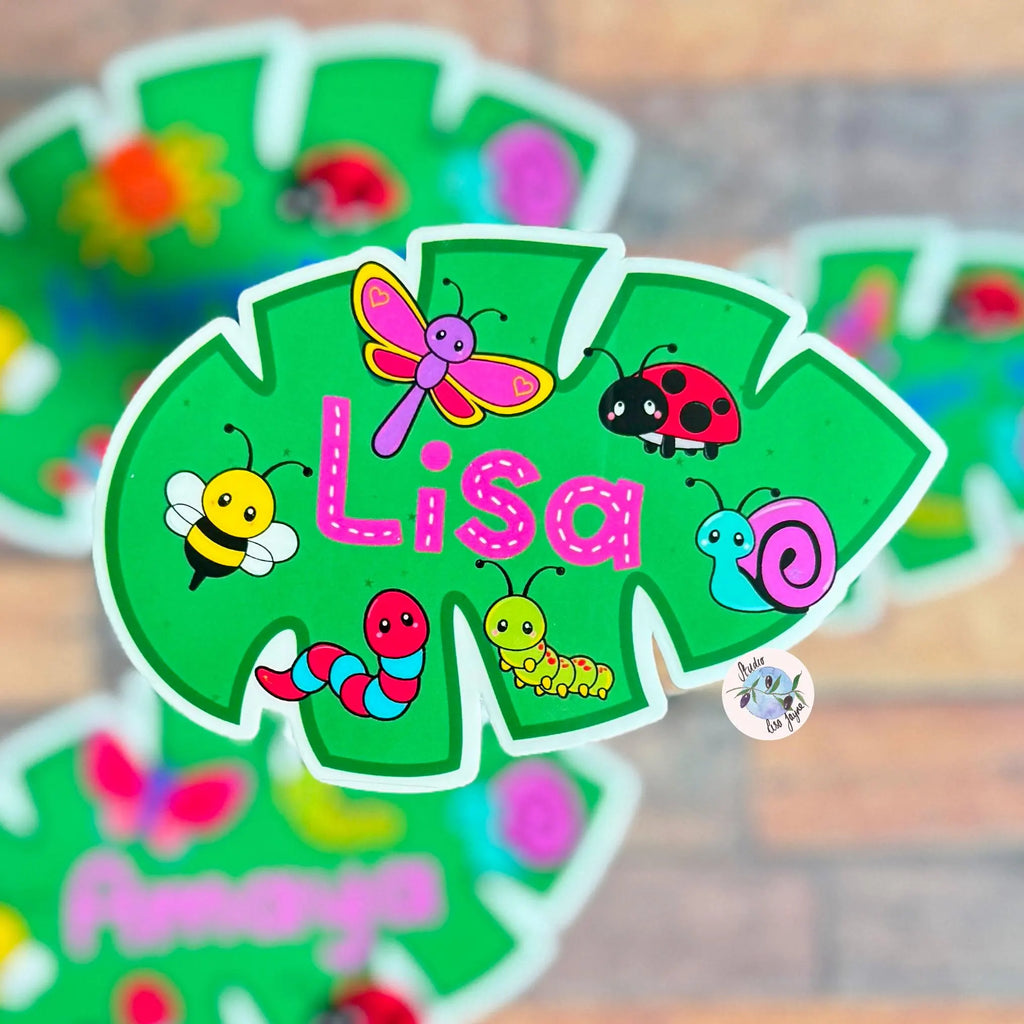 Personalized name tag with cartoon insects and the name 'Lisa' on a green background.