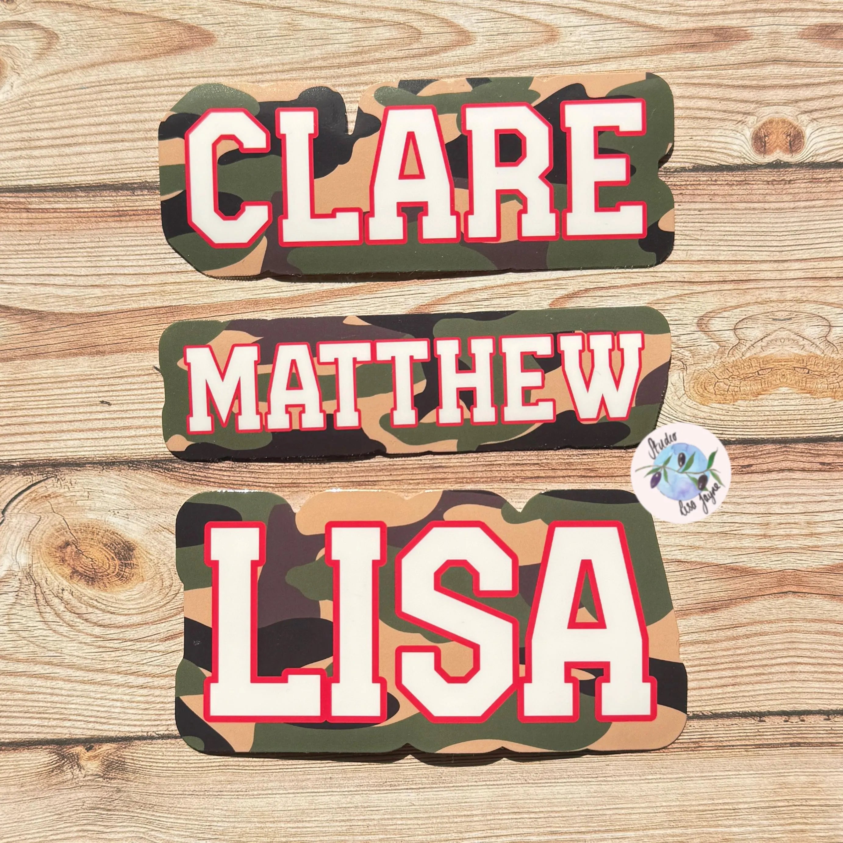 Camouflage name stickers with 'CLARE', 'MATTHEW', and 'LISA' on a wooden background