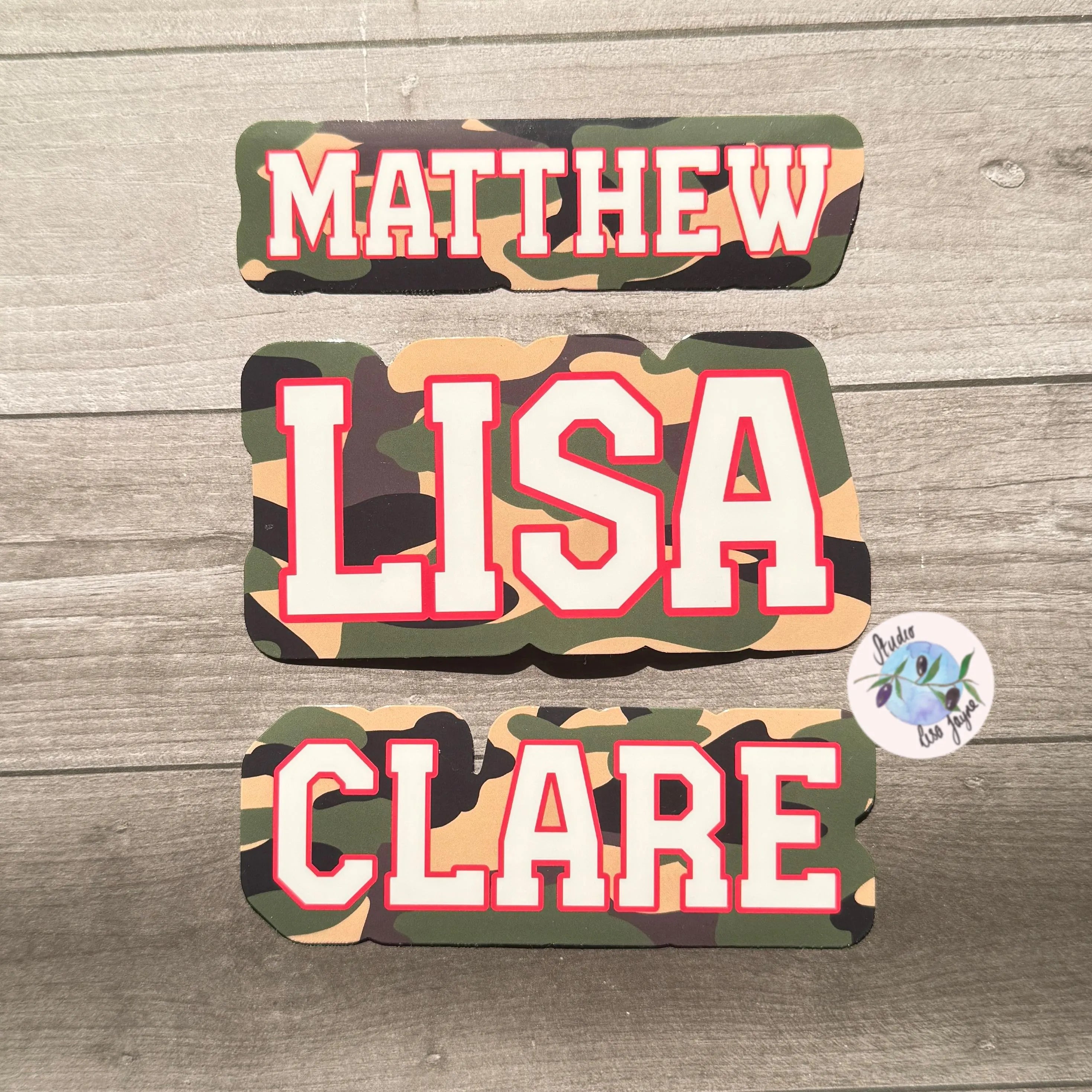 Camouflage name labels with 'MATTHEW', 'LISA', and 'CLARE' on a wooden surface.