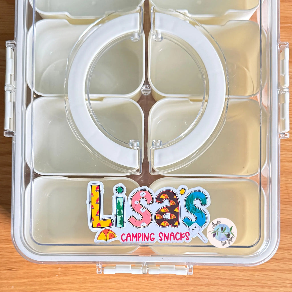 Clear compartmentalized container with 'Lisa's Camping Snacks' customised label on a wooden surface