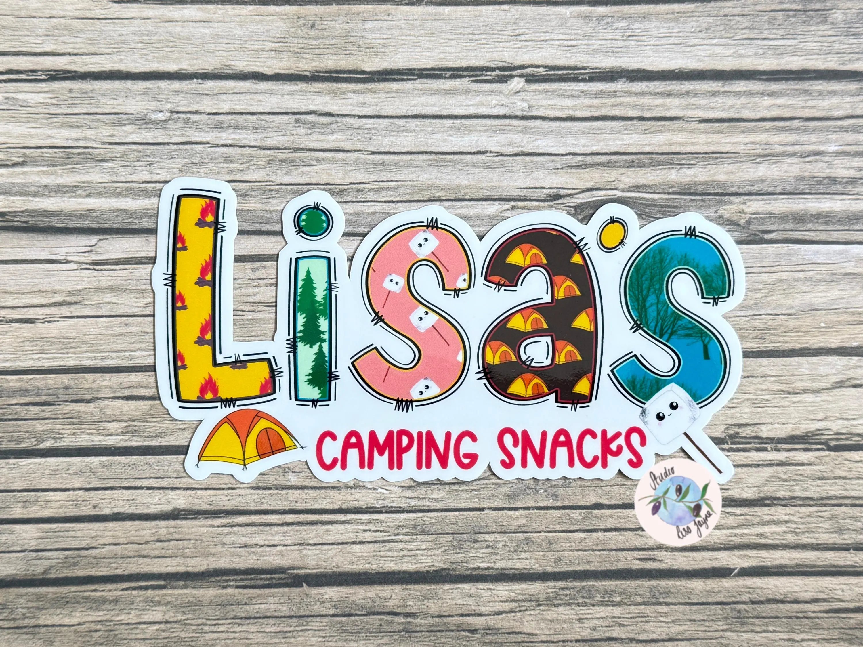 Colorful sticker with 'Lisa's Camping Snacks' text on a wooden surface