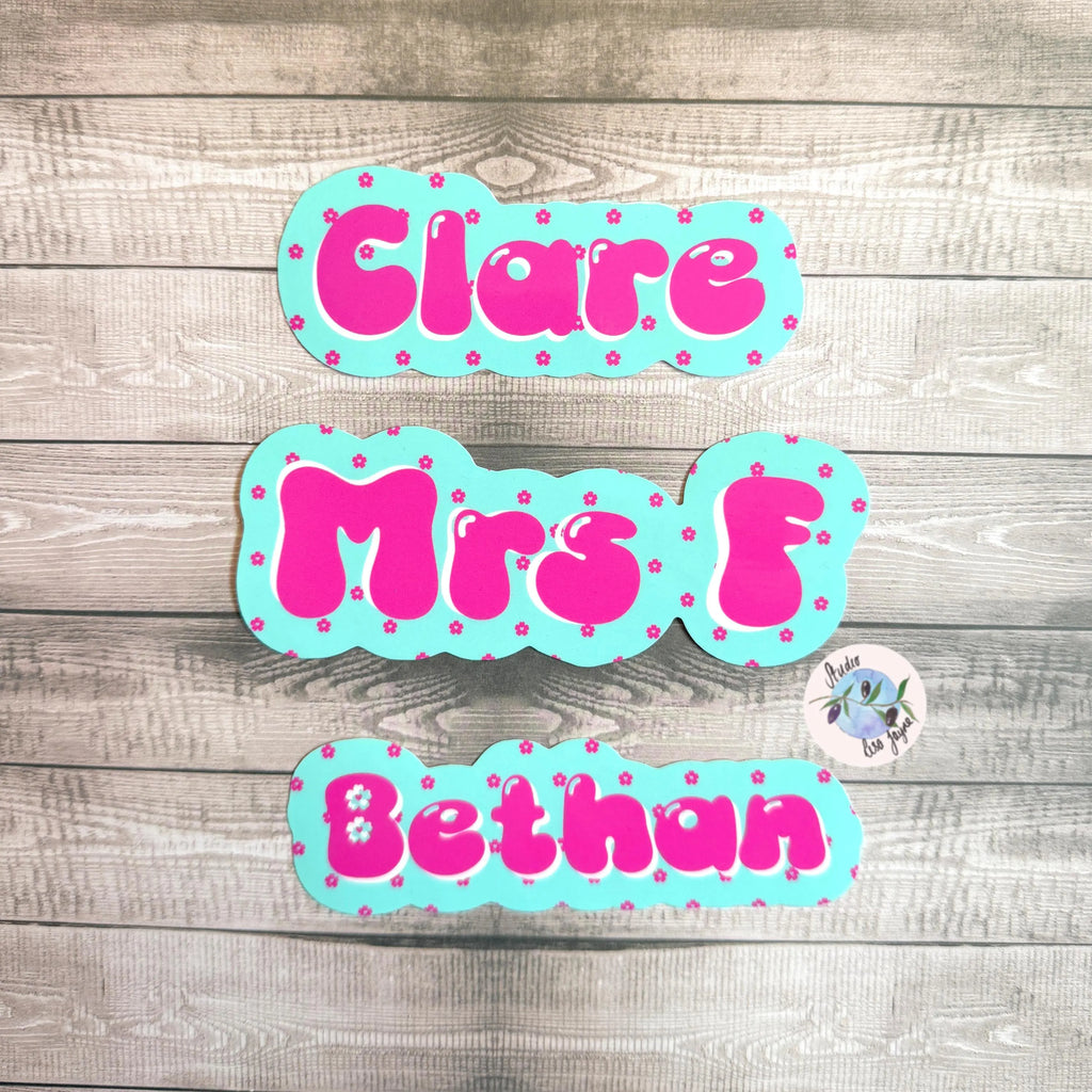 Three colorful cherry blossom name decals on a wooden surface