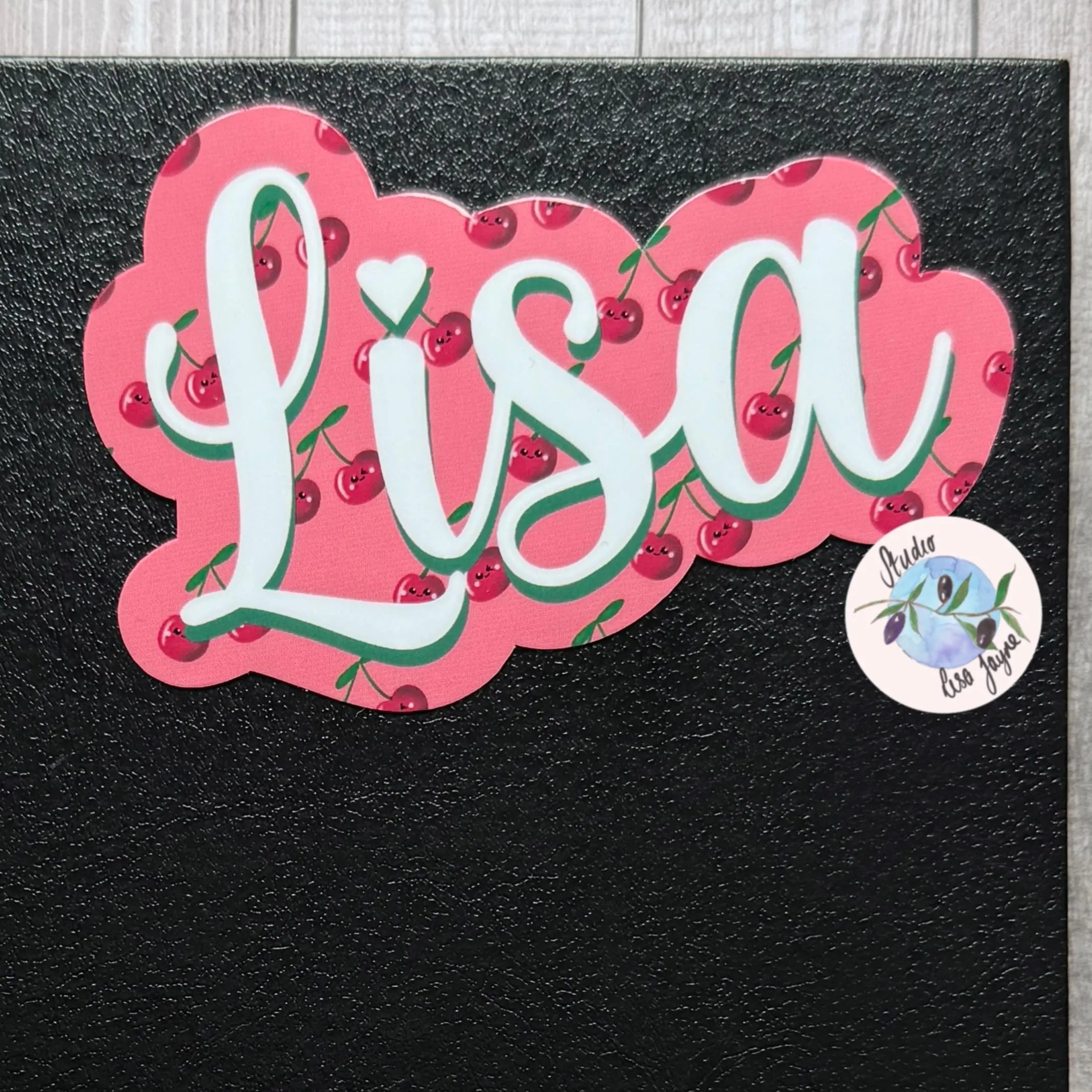 Sticker with the name 'Lisa' surrounded by cherries on a black background