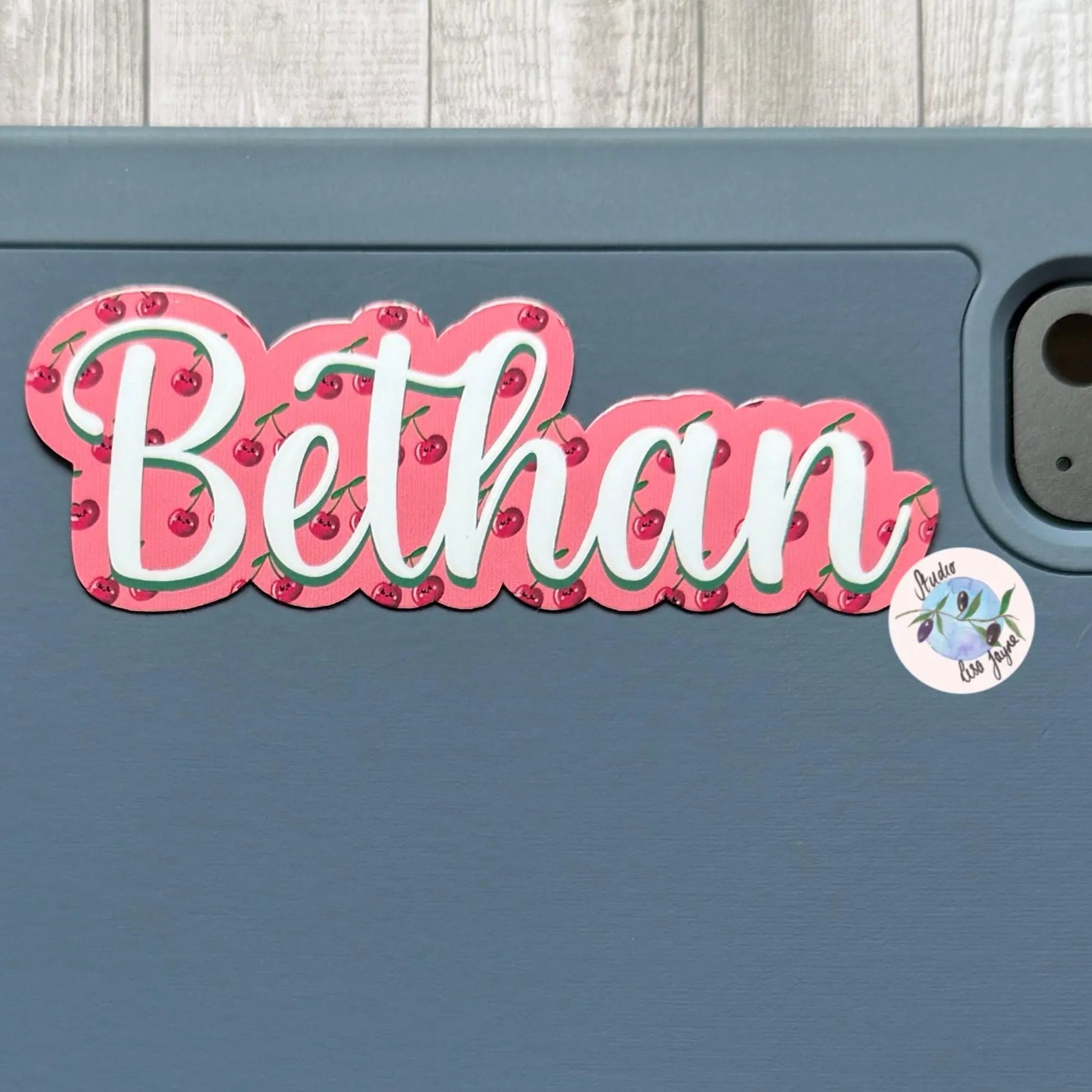 iPad tablet case with 'Bethan' cherry themed sticker on a wooden surface