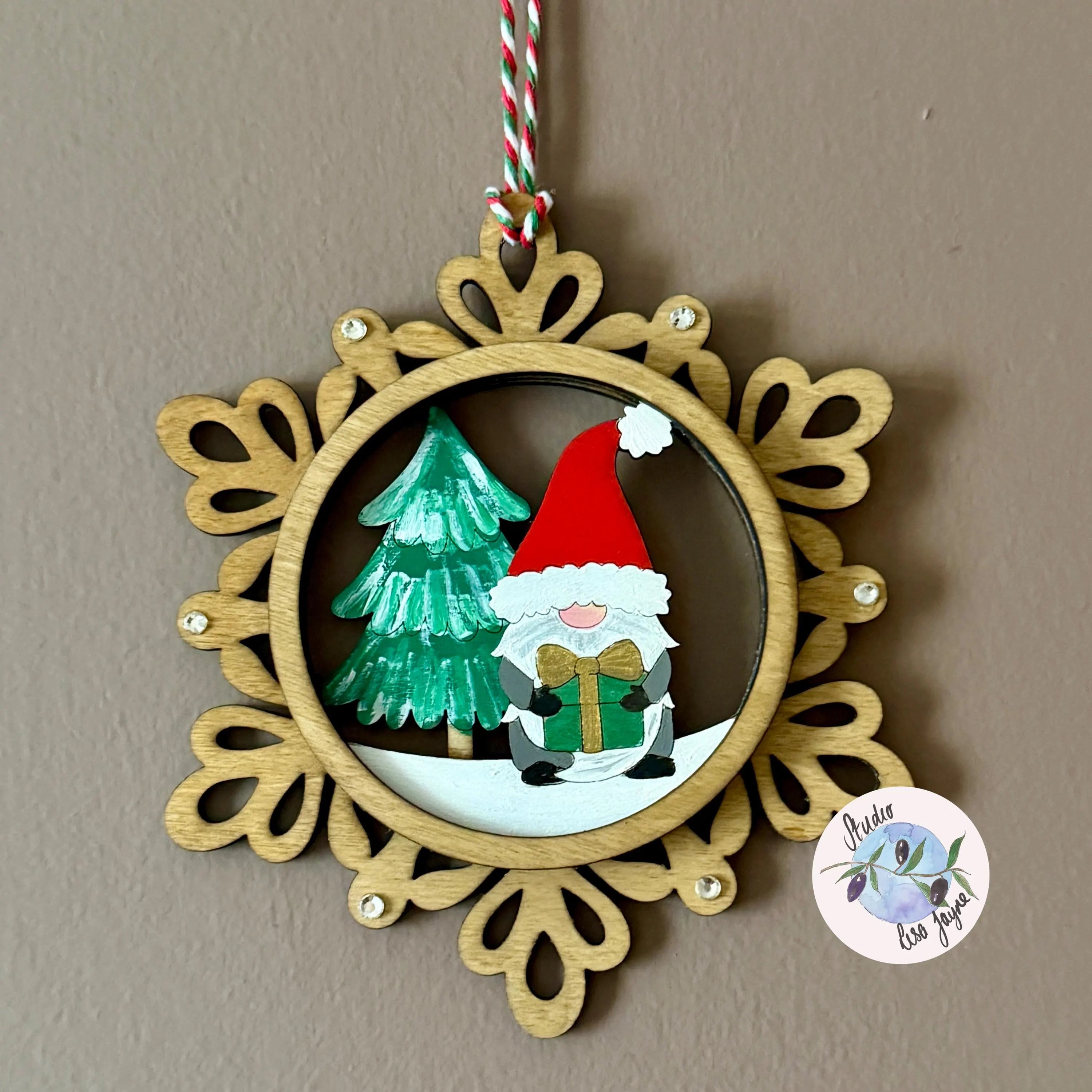 Decorative Christmas ornament with a wooden frame, Santa Claus, and Christmas tree on a brown background.