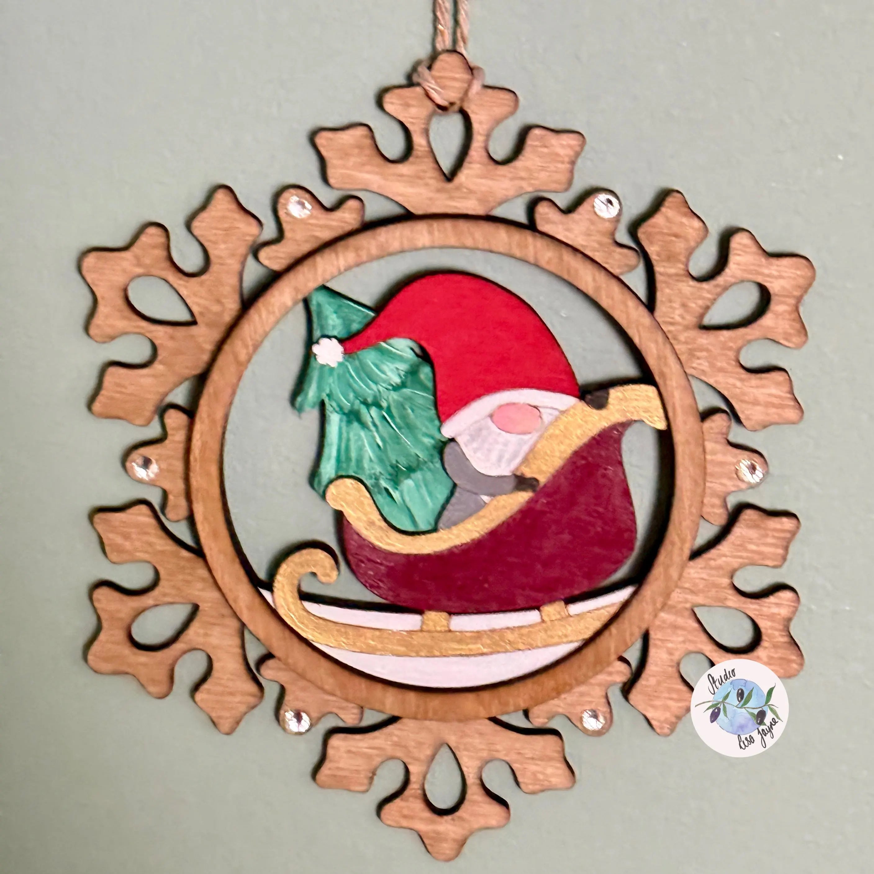 Wooden snowflake-shaped ornament with a gnome and tree design on a gray background