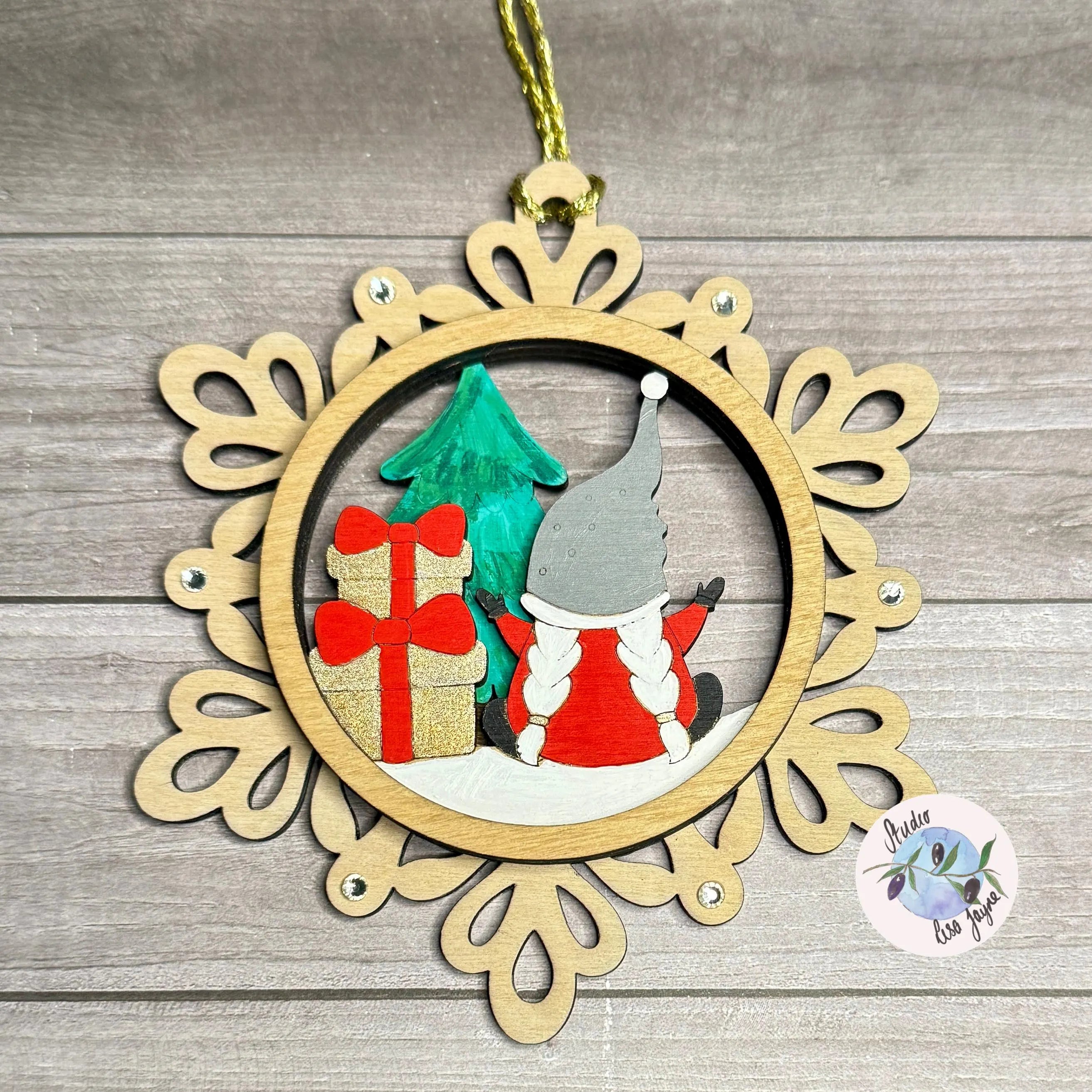 Handpainted Christmas ornament with a gnome and presents on a wooden background