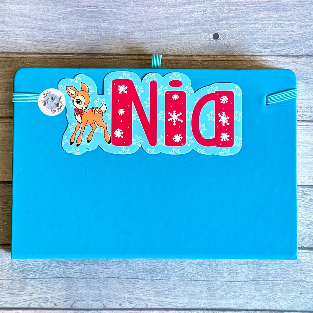 Blue notebook, diary journal with a 'Nia' and a deer design decal on a wooden surface