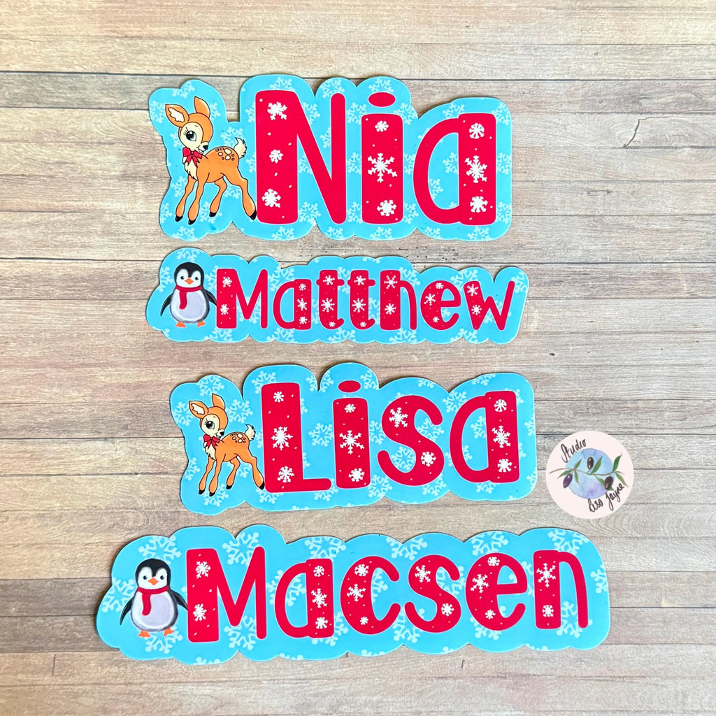 Decorative name stickers with cartoon penguin, deer and snowflakes on a wooden surface
