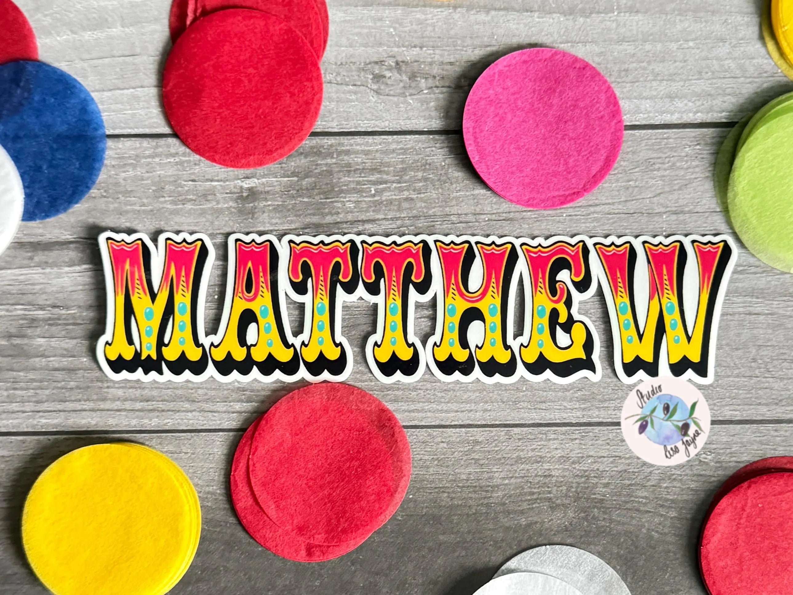 Colorful Circus name vinyl sticker spelling 'MATTHEW' on a wooden surface with multicolored circles.