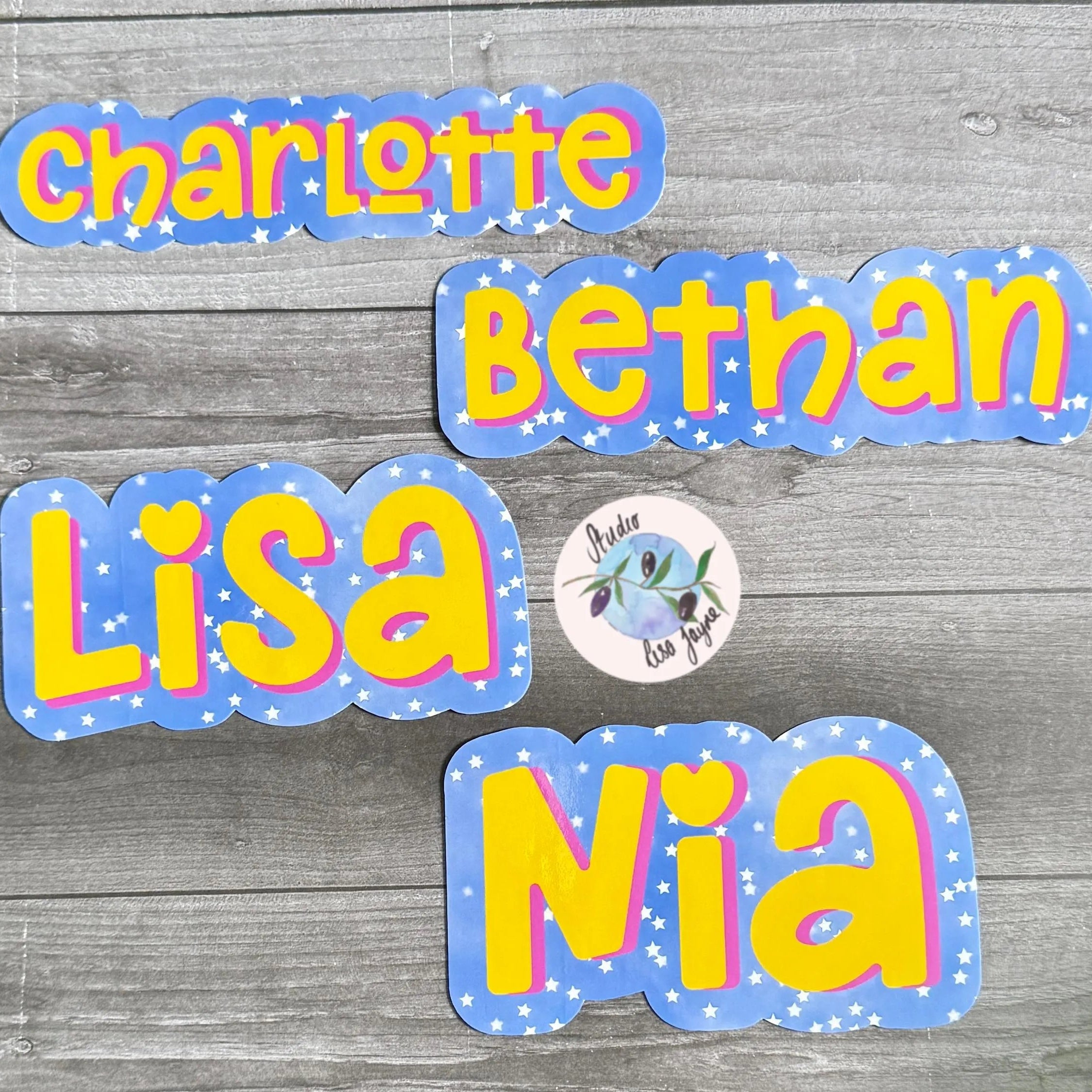 Colorful name decals for Charlotte, Bethan, Lisa, and Nia on a wooden background