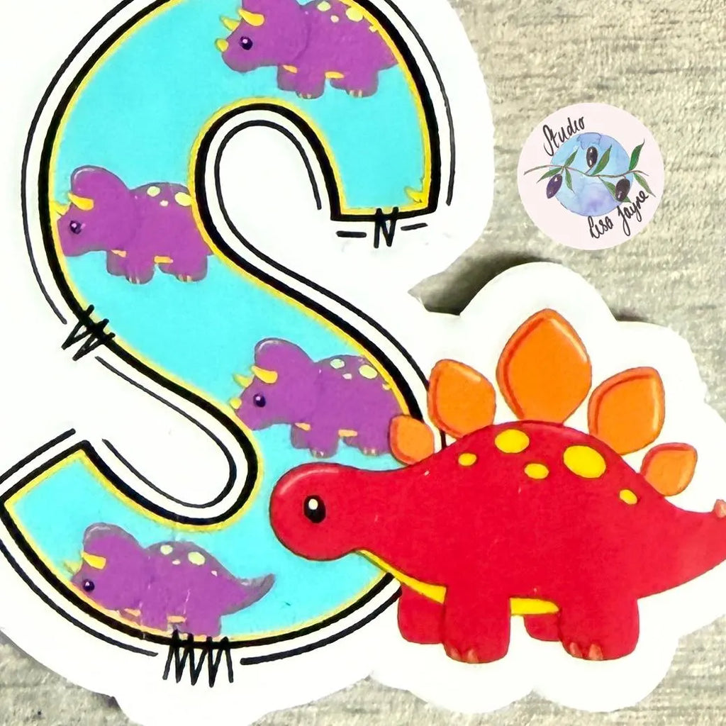 Colorful dinosaur stickers with a letter 'S' on a textured background