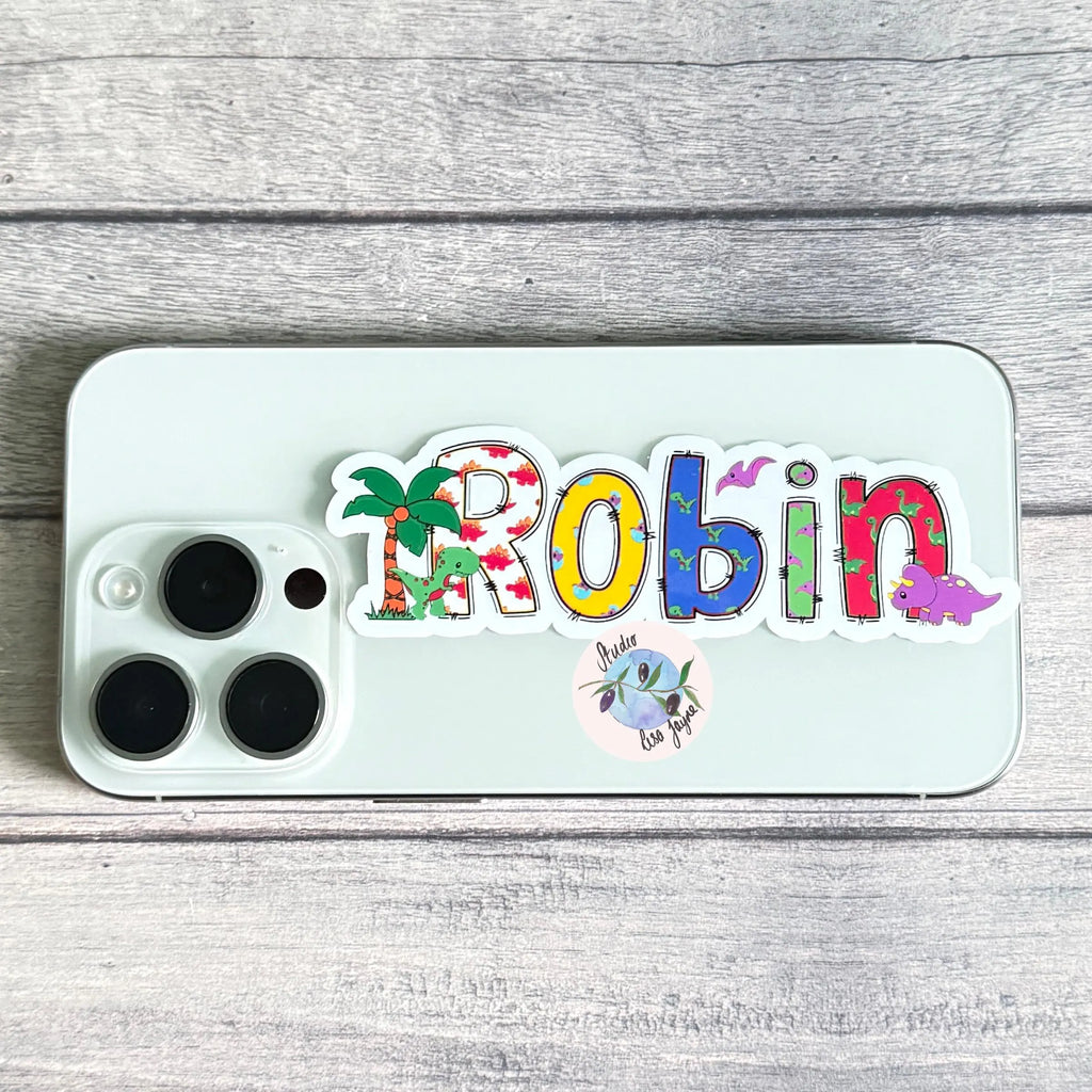 Phone case with colorful 'Robin' dinosaur sticker design on a wooden surface