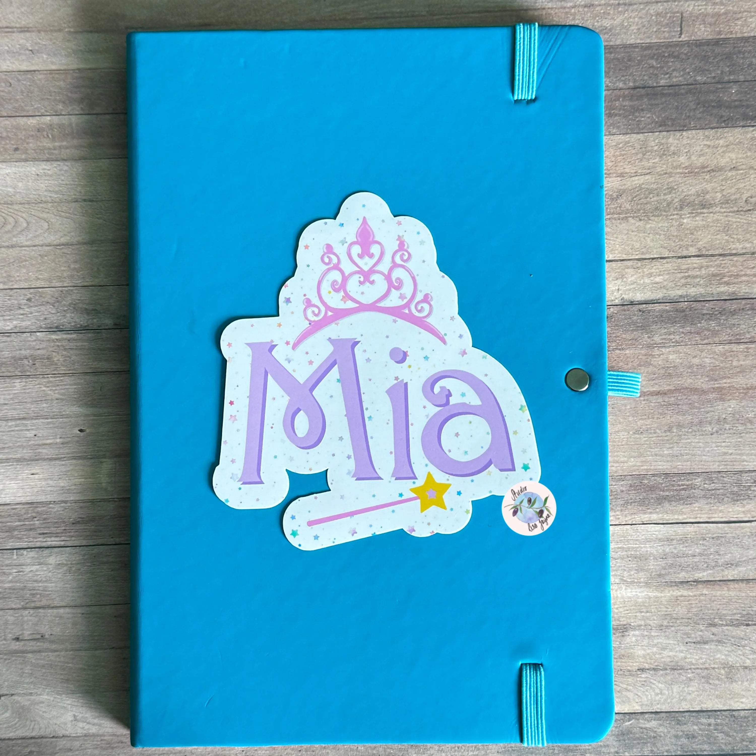 Fairy Princess themed decorative sticker on a blue notebook with a on a wooden surface
