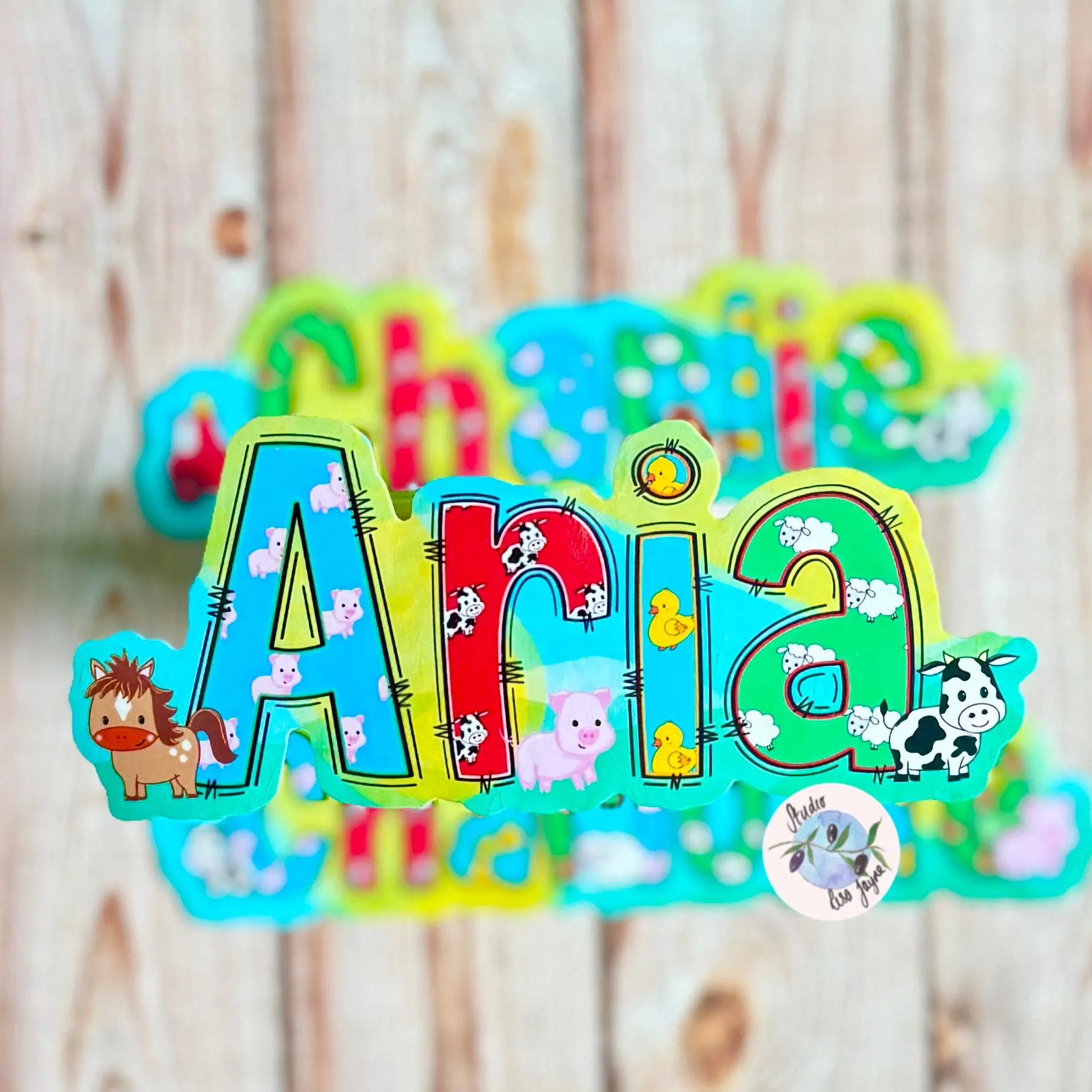 Colorful name decor with 'Aria' and farm animal illustrated name sticker on a wooden background