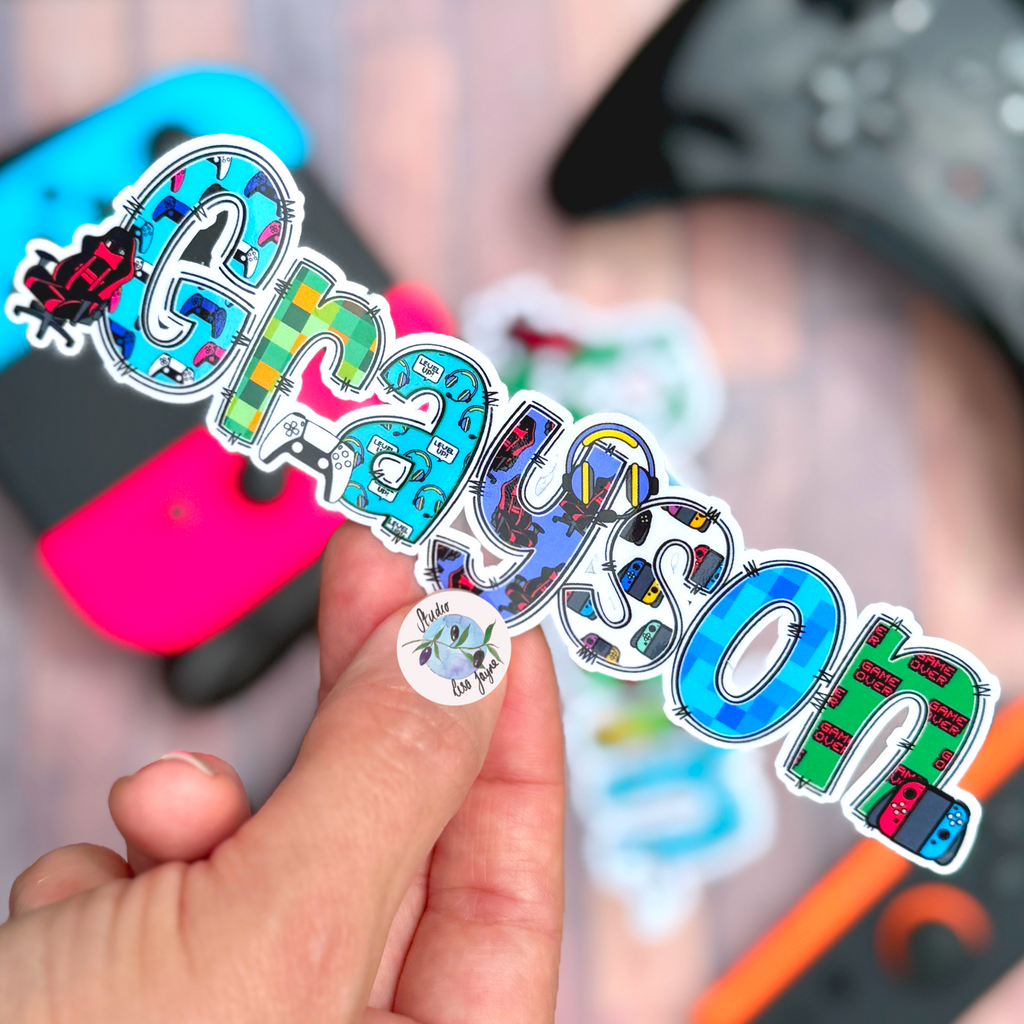 Gamer Name Stickers - Computer Game Geek Video Games Waterproof  Photo Album Name Labels Personalised Decals PlayStation and switch theme held in front of console controllers