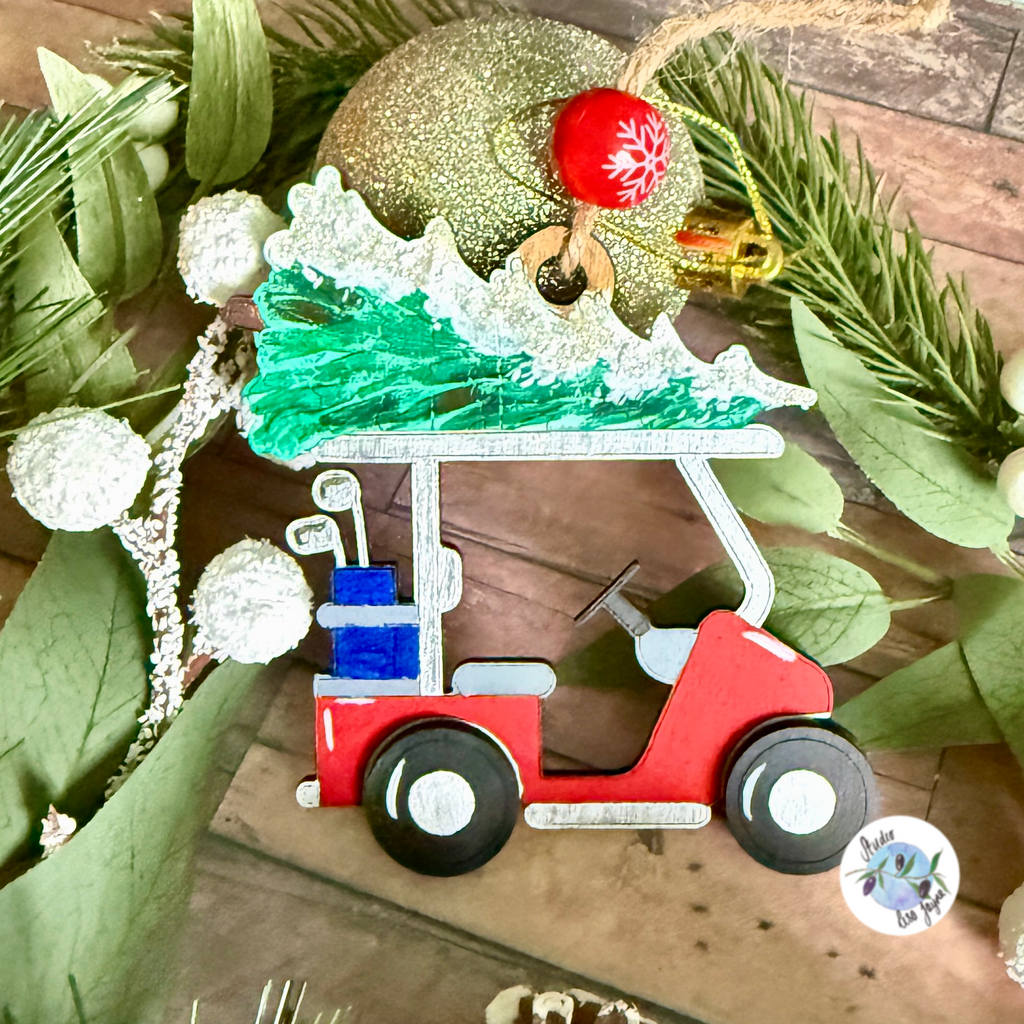 Christmas decoration of a red golf cart with a green xmas tree on a wooden surface with greenery.