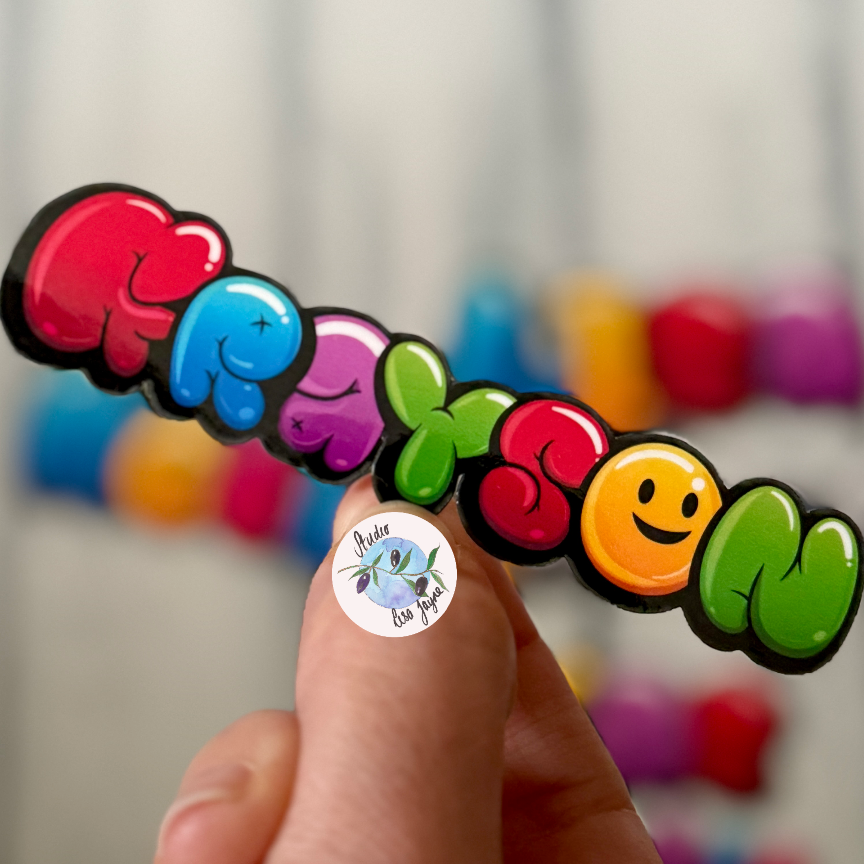 Graffiti Bubble Balloon Name Sticker Personalised - Colourful Grayson label with yellow smiley face in hand for scale 