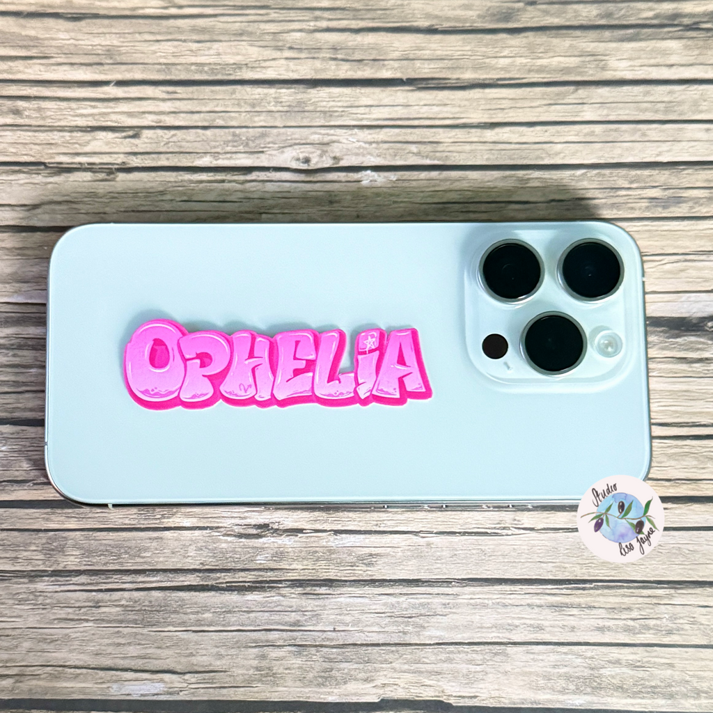 Phone with 'Ophelia' pink graffiti name sticker on a wooden surface