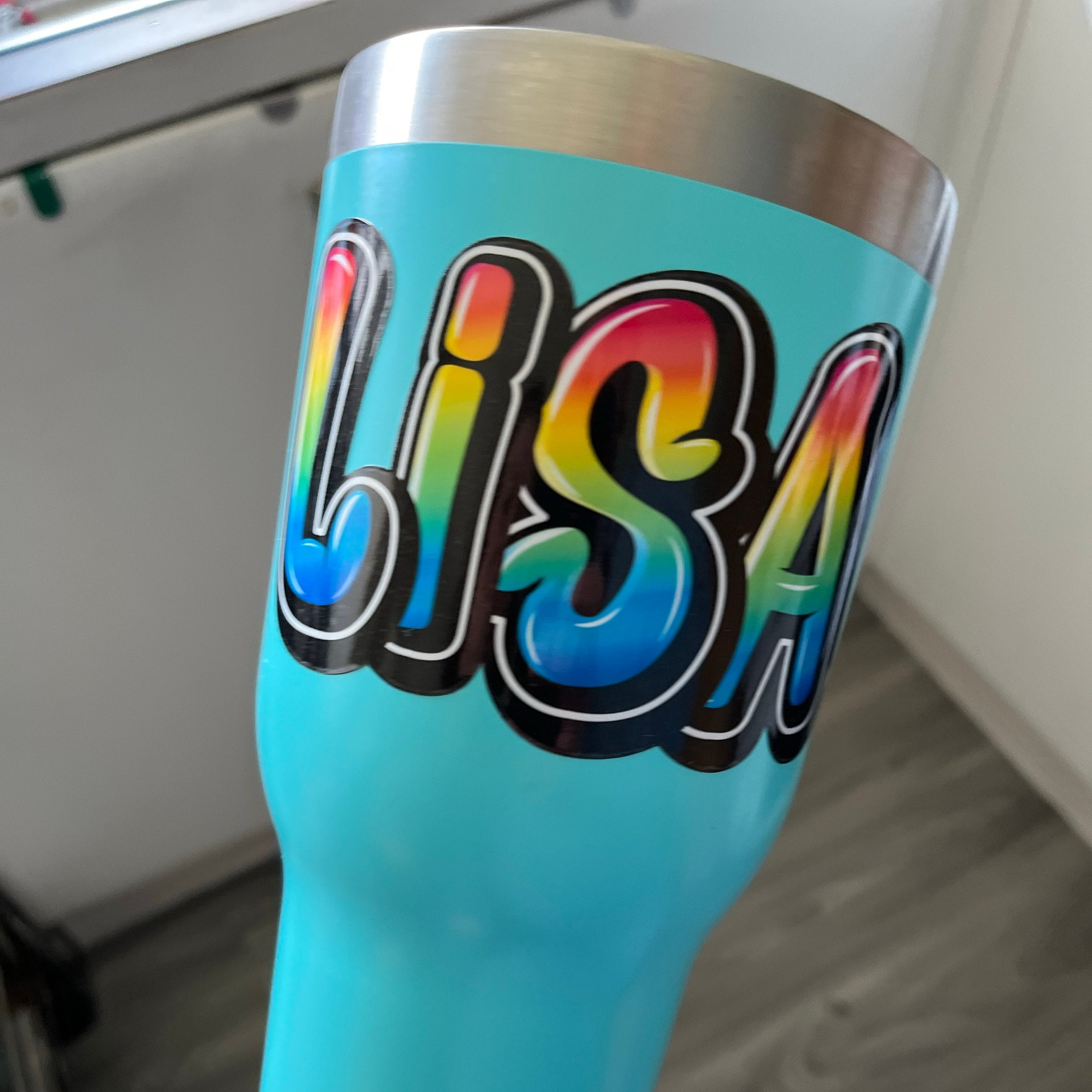 Rainbow style graffiti name sticker on a drink bottle