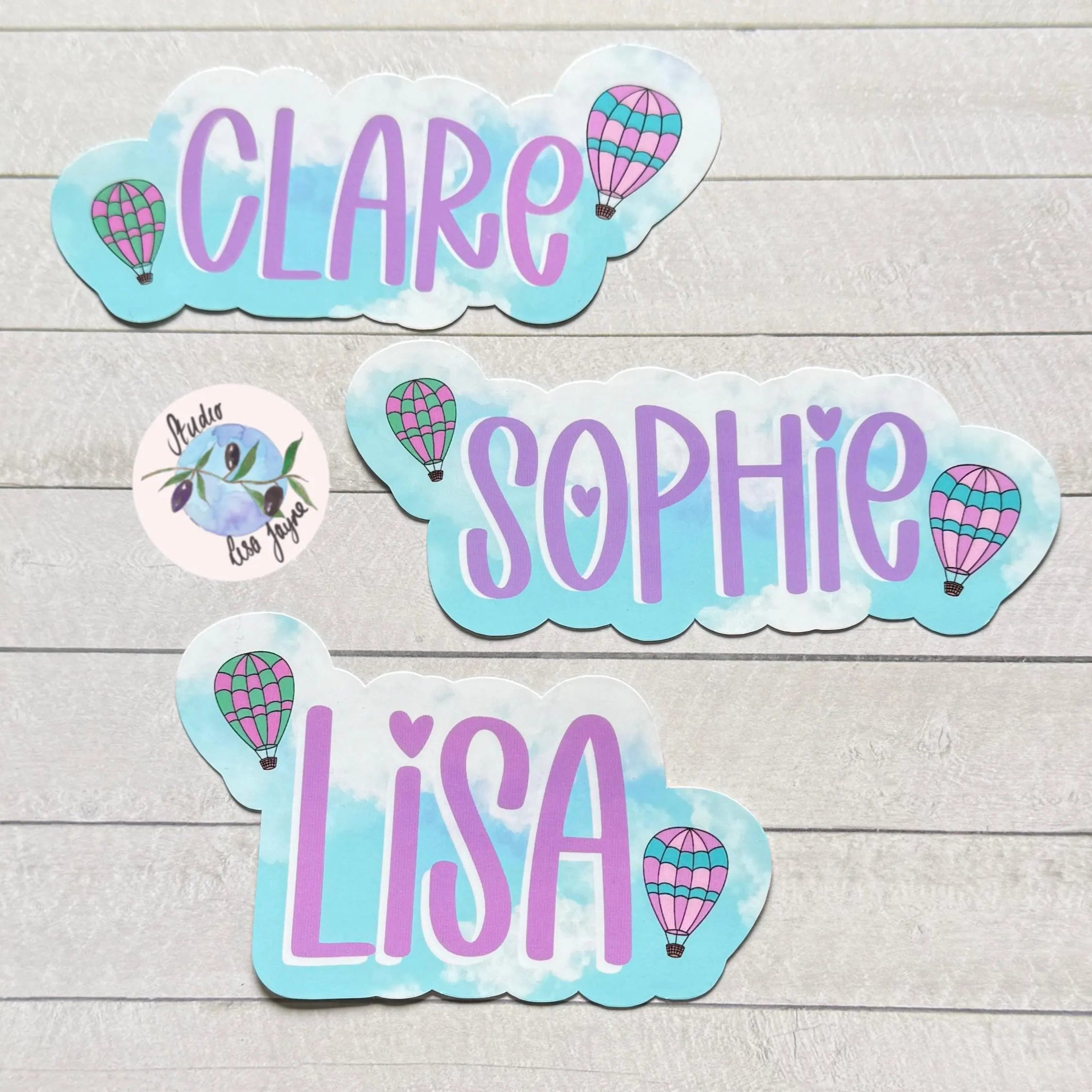 Stickers with names 'Clare', 'Sophie', and 'Lisa' on a wooden surface