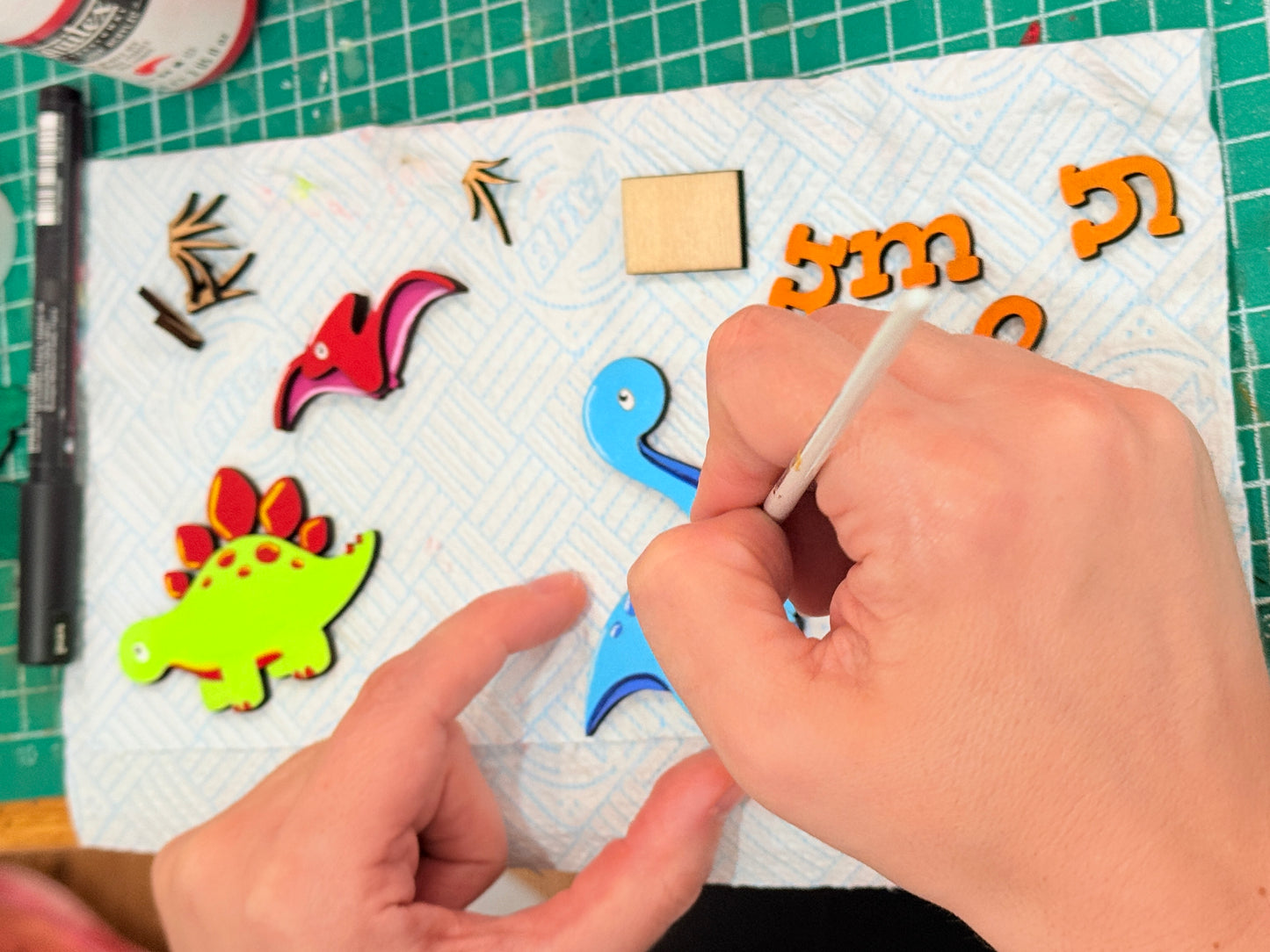 Dinosaur personalised kids name plaque sign plate.  Colourful hand painted children’s bedroom door - Lisa’s hands as she paints the creatures ready to be assembled