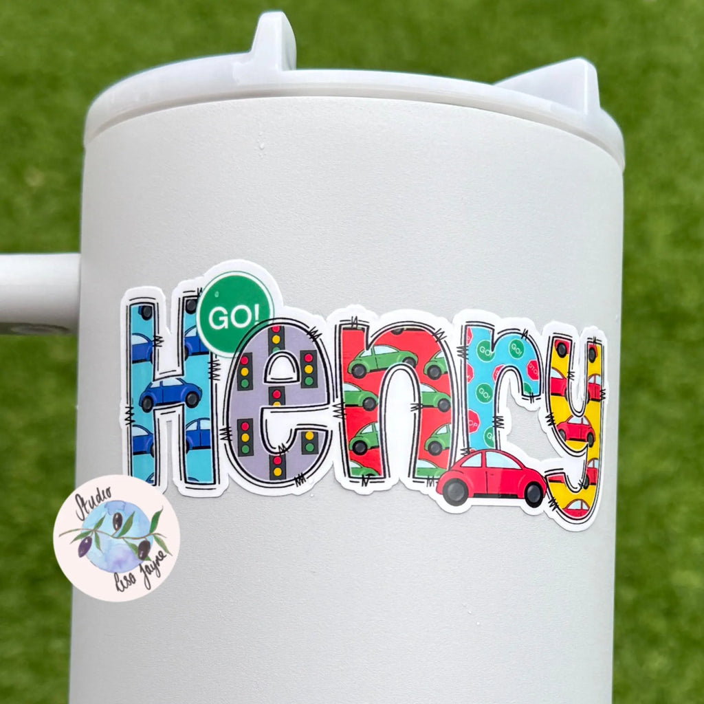 Colorful 'Henry' car themed sticker on a white cup with a green grass background