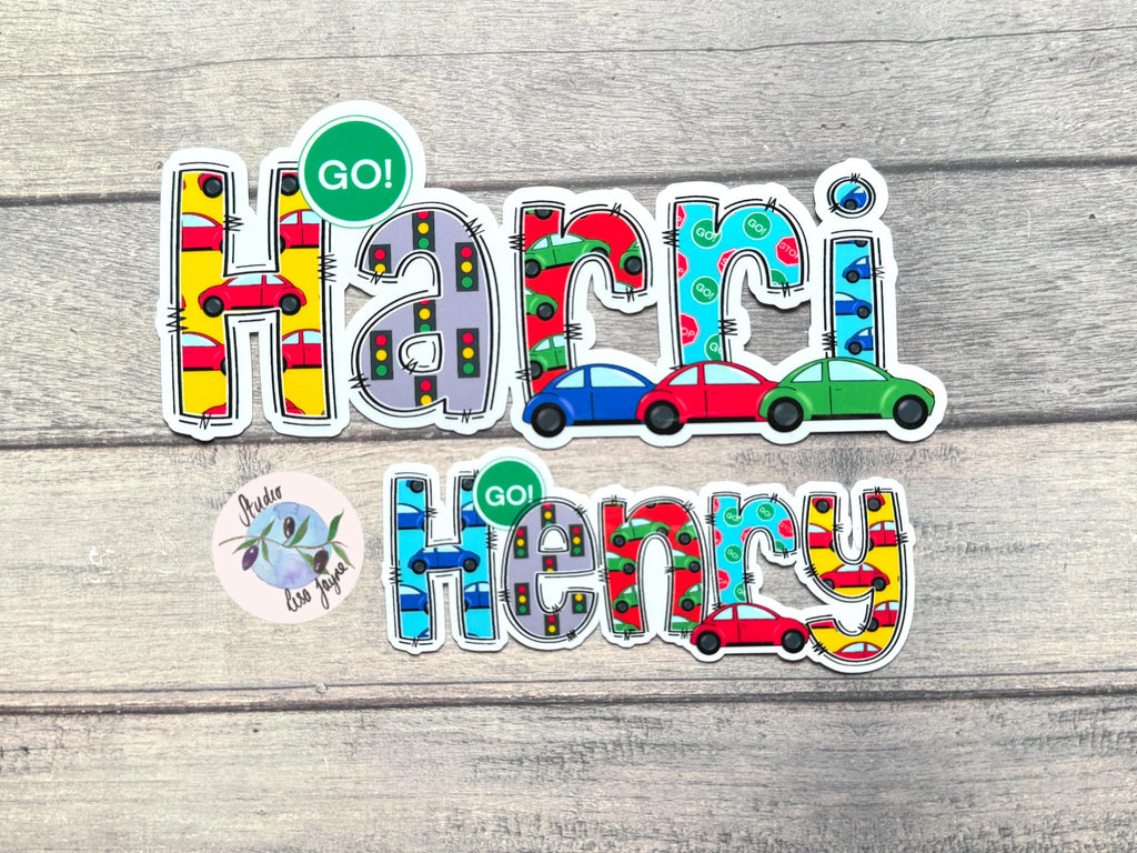 Colorful 'Harri! Henry' stickers in a car theme on a wooden surface