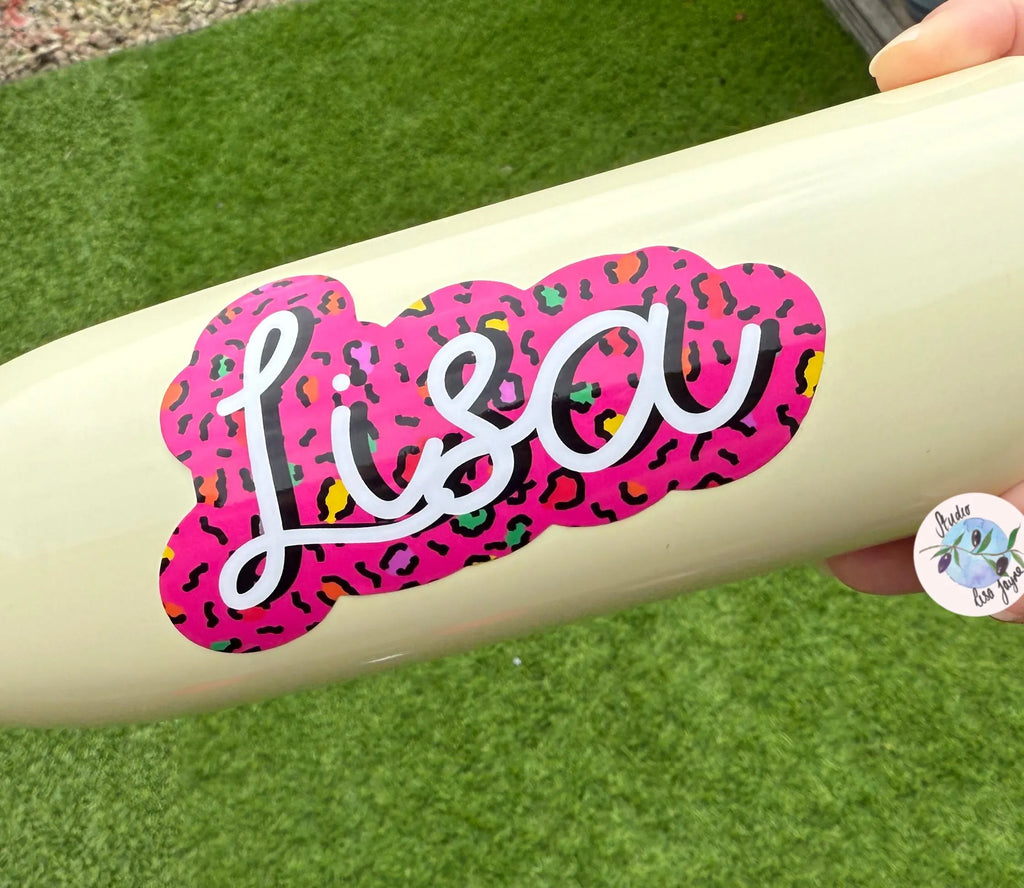 Beige water bottle with a pink and multicolor leopard print 'Lisa' sticker on a grass background