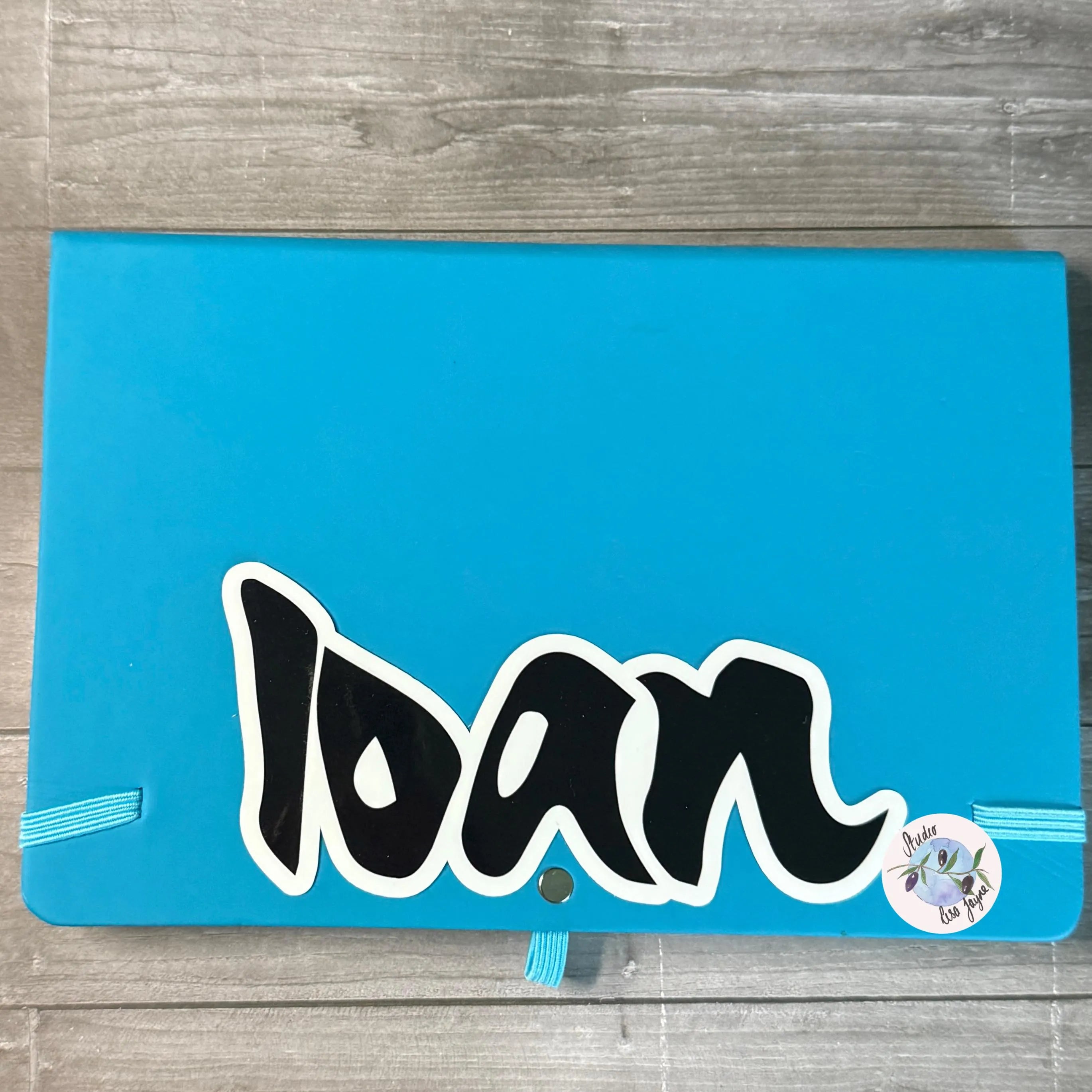 Blue notebook with 'Ioan' manga graffiti sticker