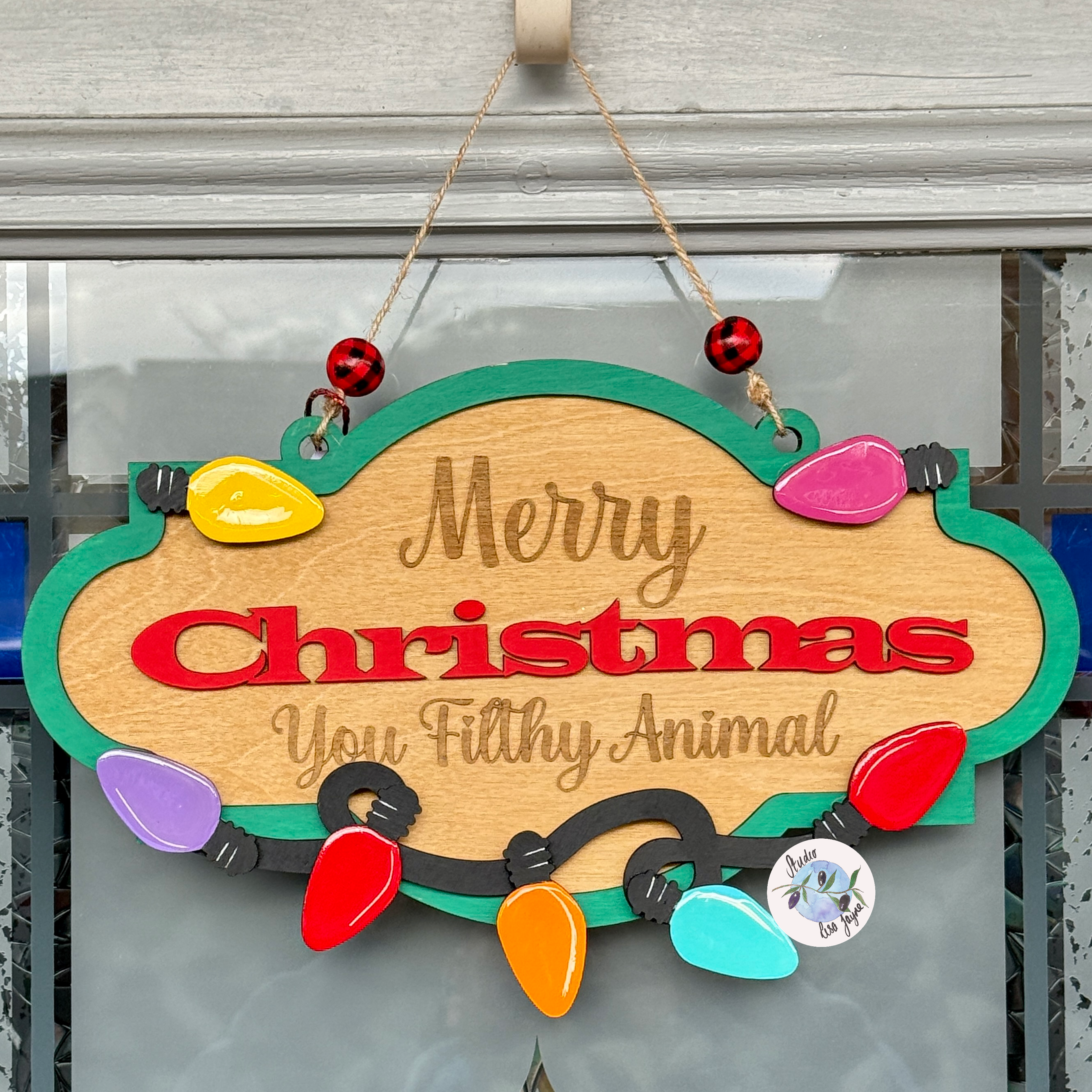 Decorative Christmas sign with colorful lights and text on a glass door.