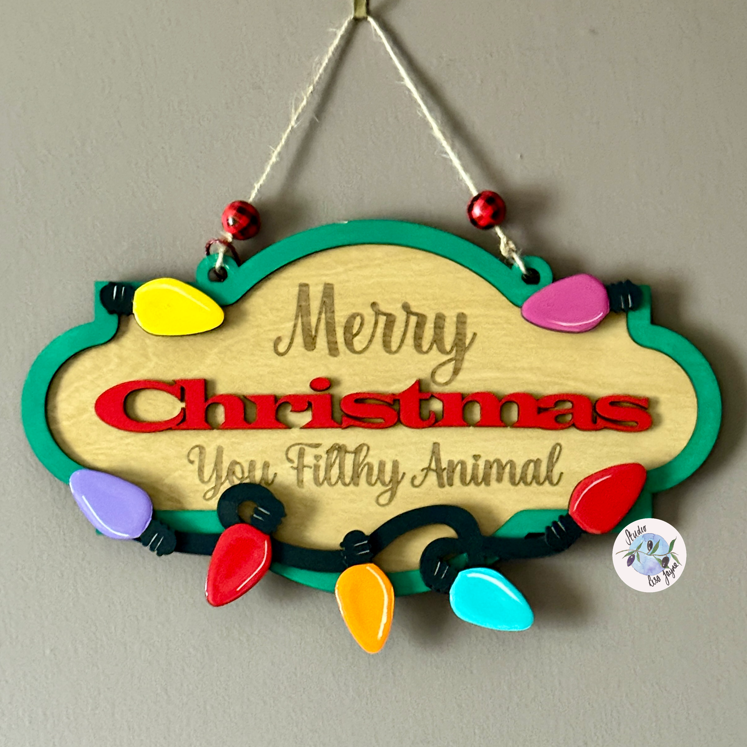 Decorative Christmas sign with colorful lights and text on a plain background