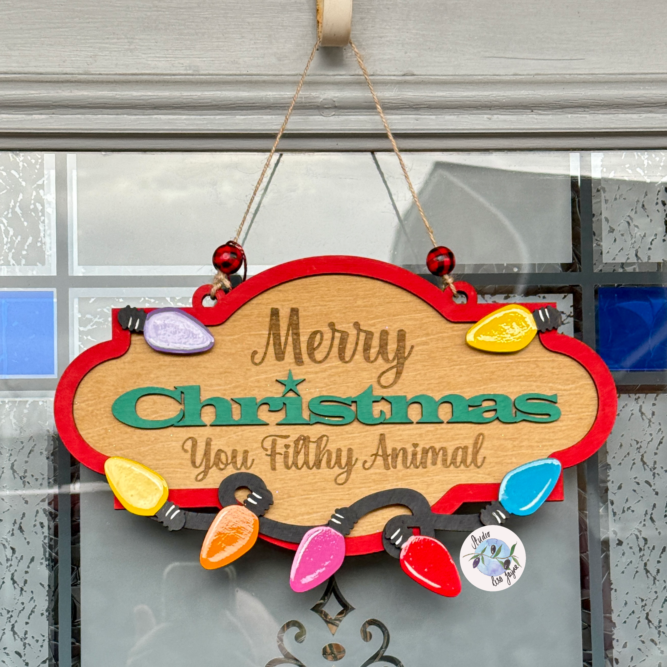 Decorative Christmas sign with colorful lights and text on a glass door.