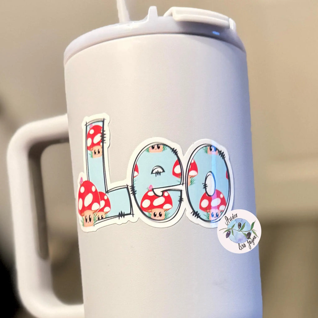 White tumbler with 'Leo' and mushroom stickers on a blurred background