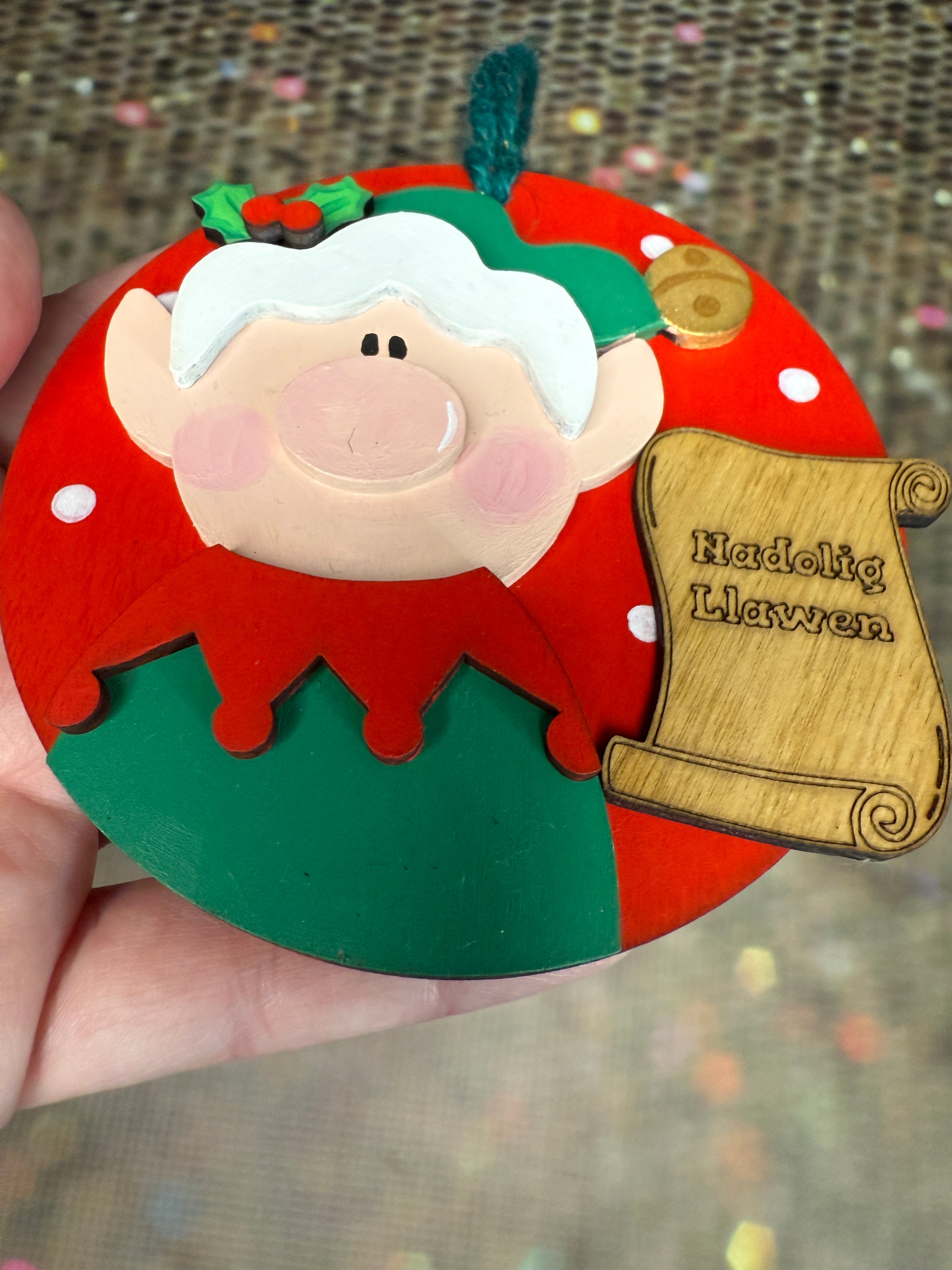 Nadolig Llawen Elf Christmas Tree Decoration Handmade Wooden Decoration Made in Wales - Green Elf on Red Backdrop showing 3D Layers