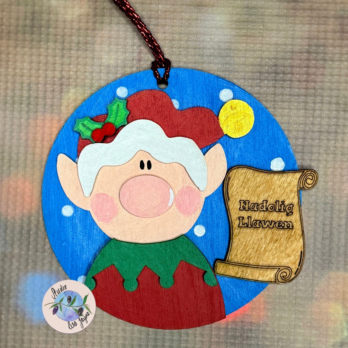 Nadolig Llawen Elf Christmas Tree Decoration Handmade Wooden Decoration Made in Wales - Red Elf on Blue Backdrop