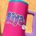 Pink water bottle with blue lid and handle, featuring the name 'Riya' in a colorful Ombré Heart Name Personalised Sticker