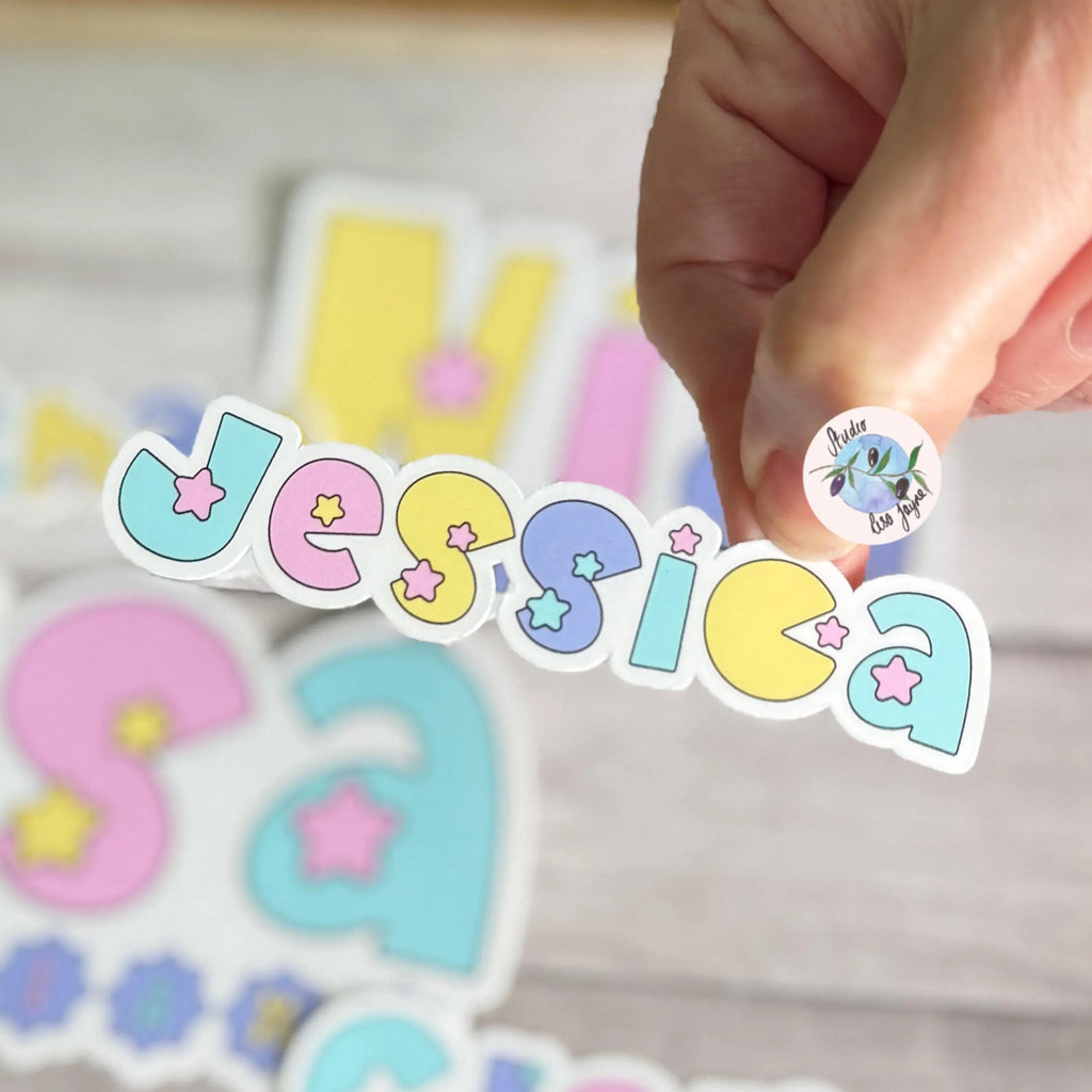 Colorful pastel star sticker with the name 'Jessica' held by a hand on a light background