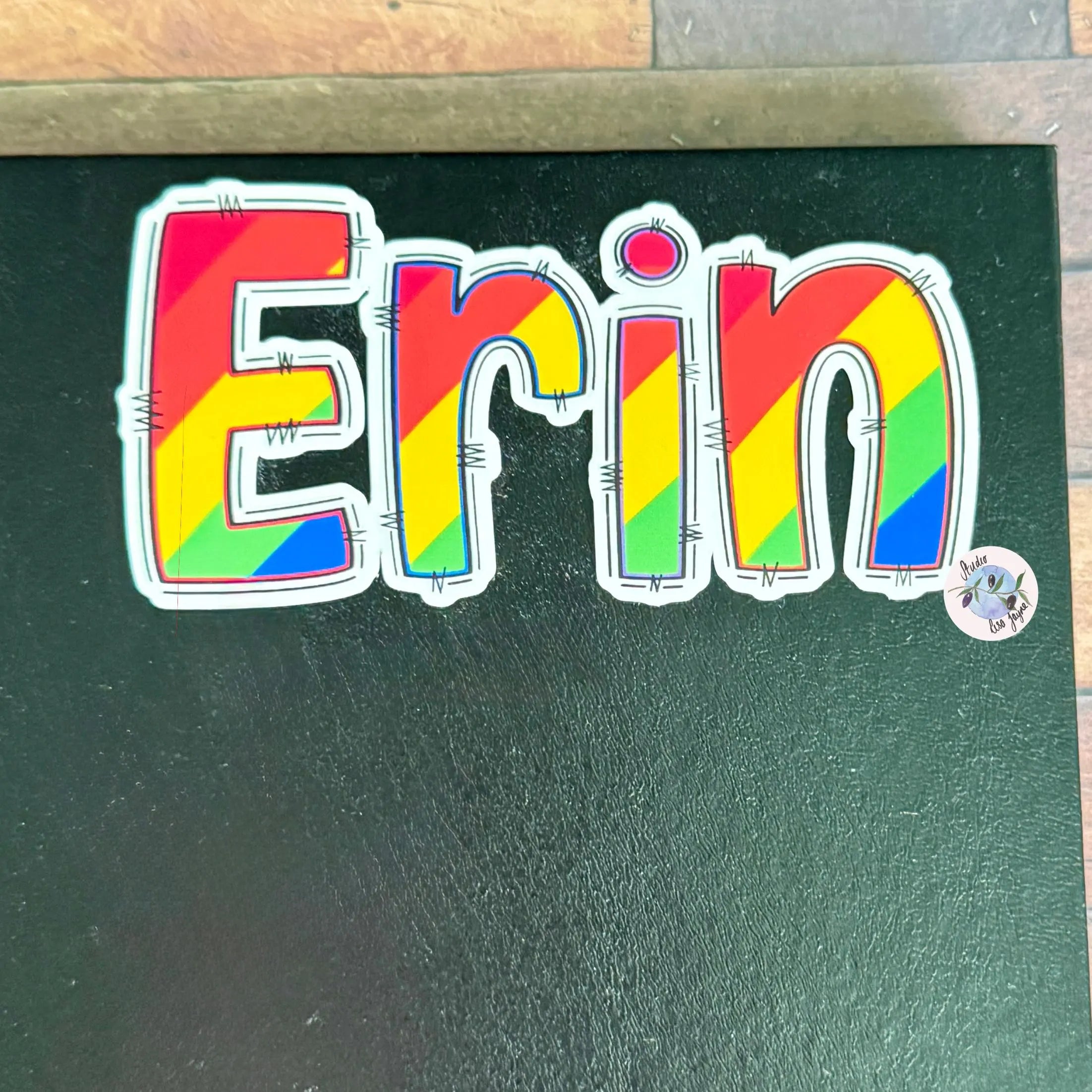Colourful Rainbow sticker with the name 'Erin' on a green surface