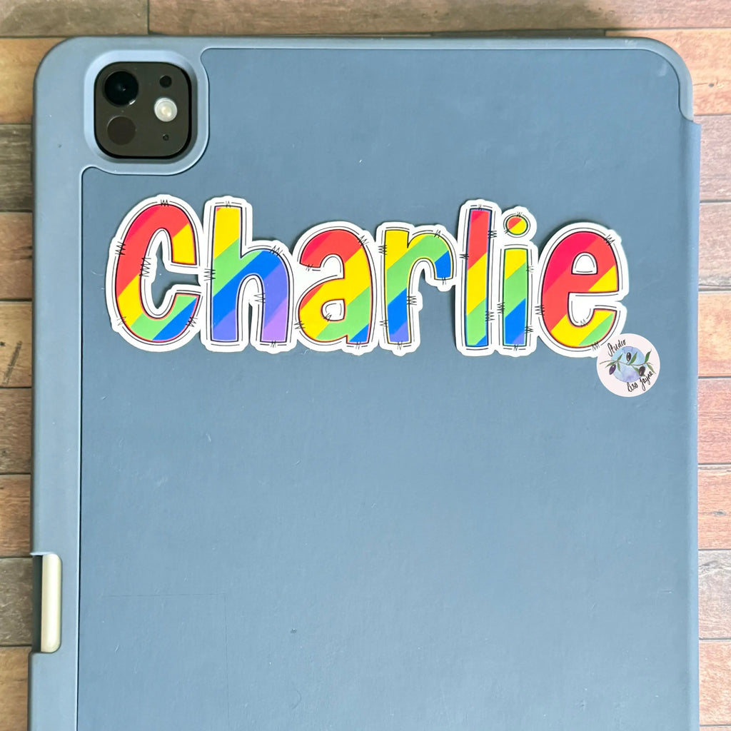 Blue tablet case with 'Charlie' Rainbow colourful letters on a wooden surface