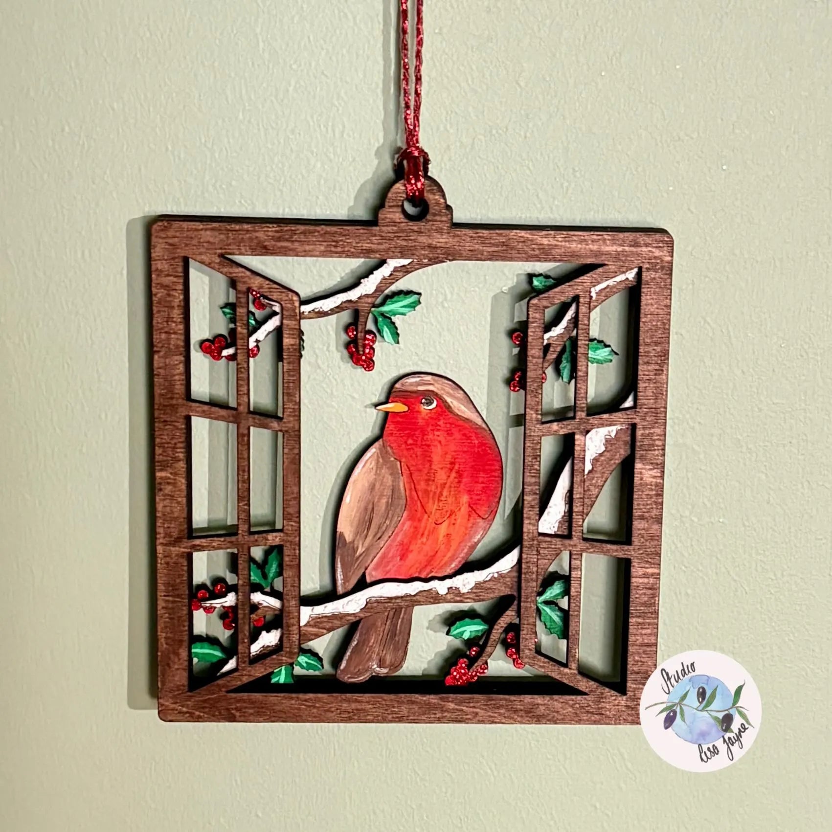 Decorative hanging Christmas ornament with a red robin bird design on a light green background
