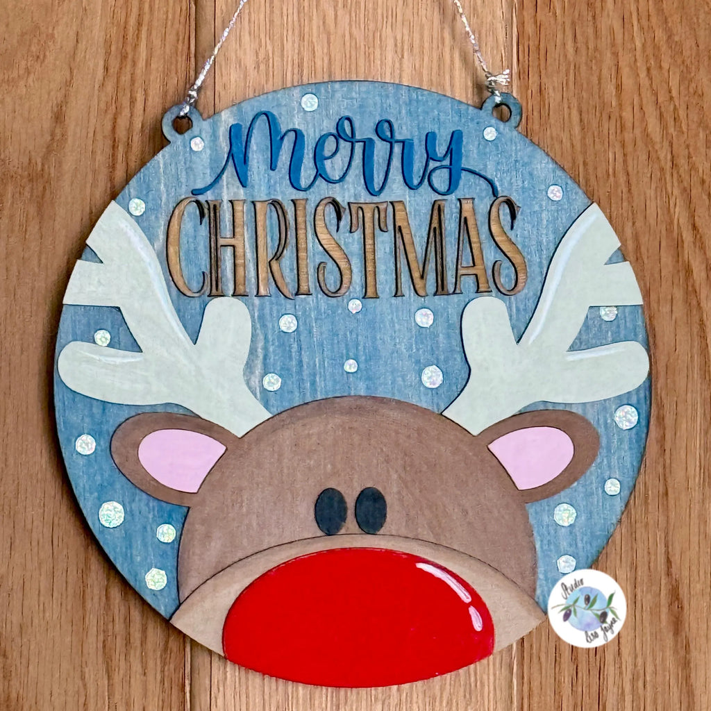 Decorative Christmas sign with reindeer face and 'Merry Christmas' text on a wooden background