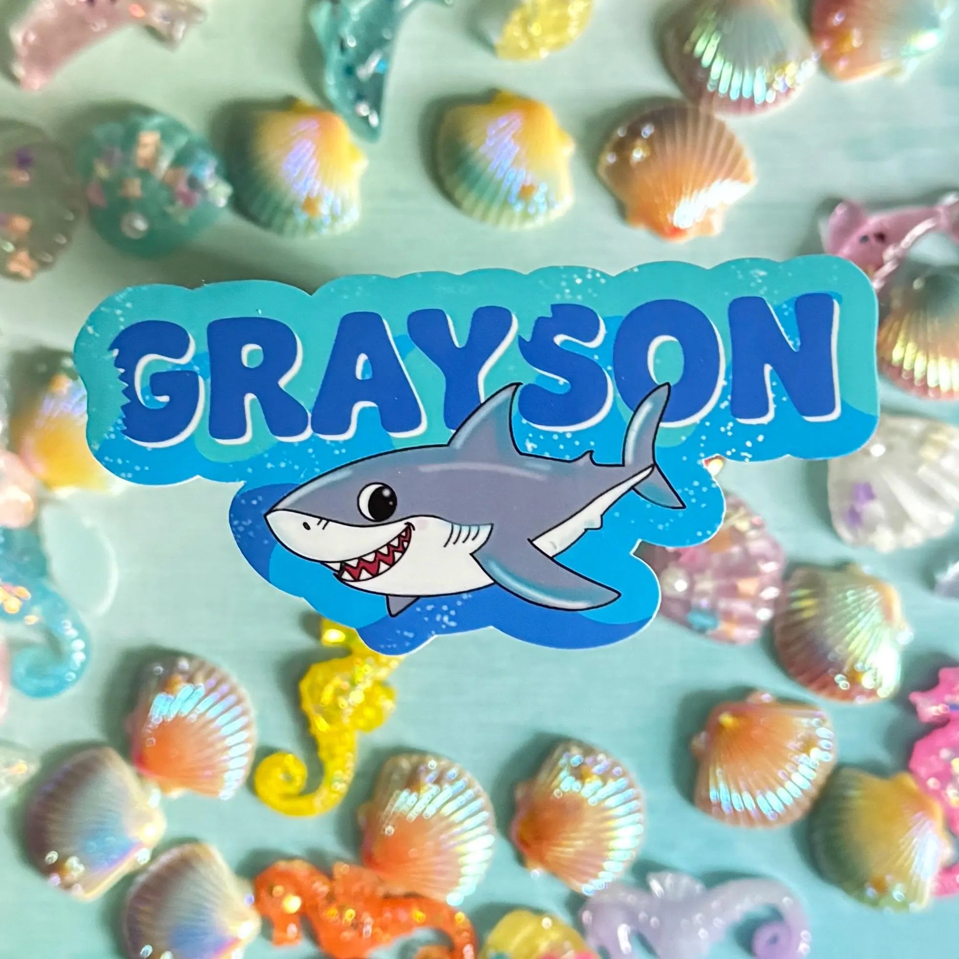 Shark themed namr Sticker with 'GRAYSON' and a shark design on a background of colorful shells and sea creatures.